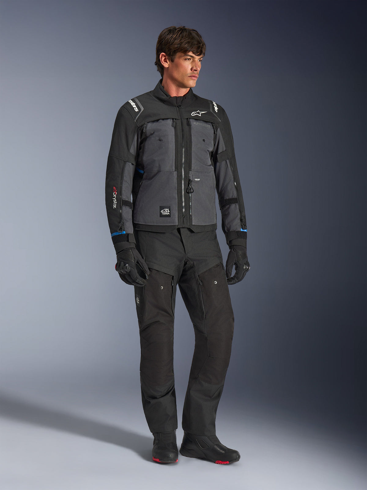 Alpinestars Cusco Drystar® Jacket in Black and Deep Gray, technical motorcycle touring jacket with multi-tonal panels, worn with matching black riding pants and gloves, designed for road and adventure touring.