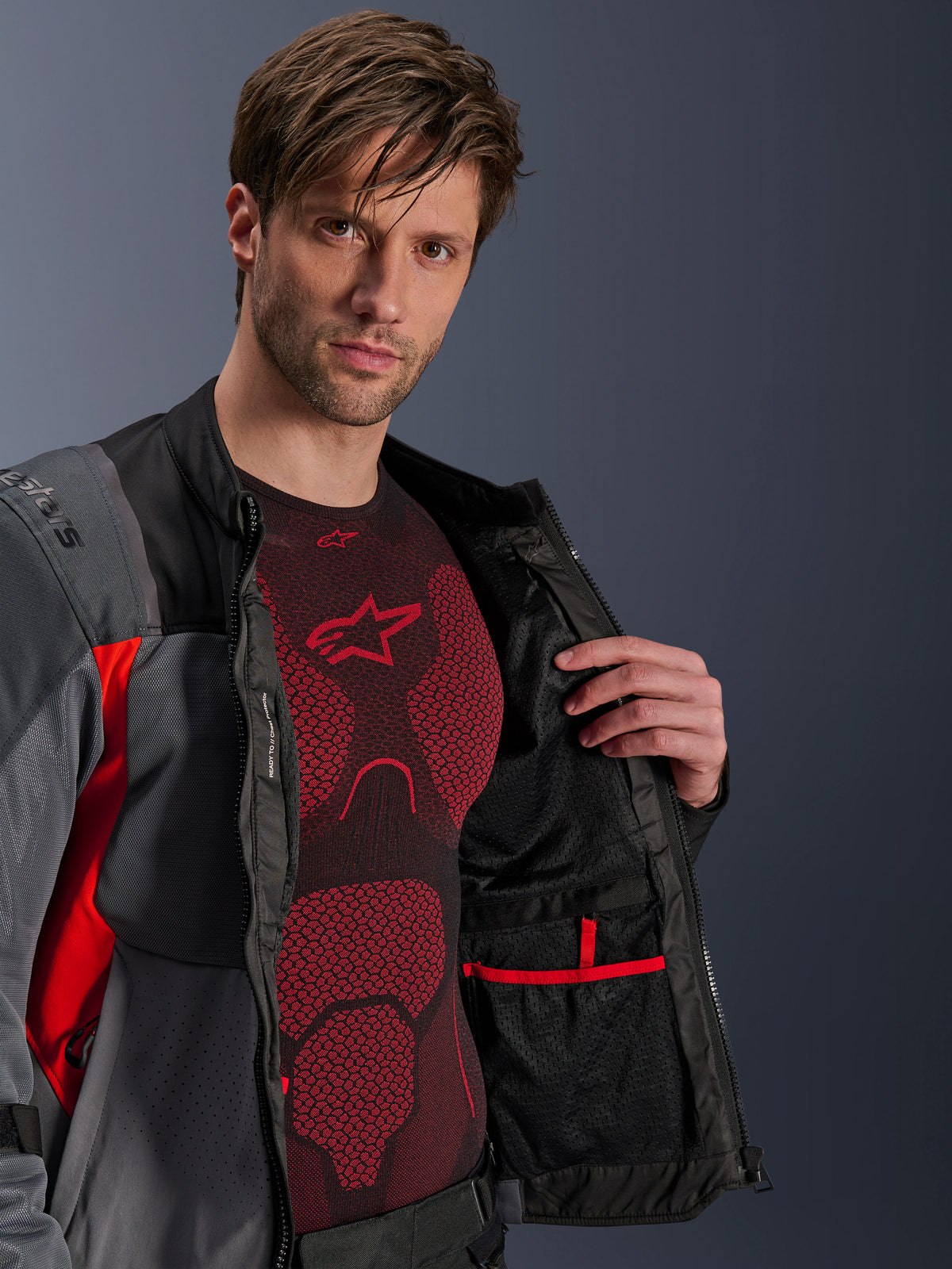 Alpinestars ST-2 Air jacka, motorcykeljacka för adventure touring, herr, grå och röd, öppen med synligt nätfoder och innerficka, bärs över ett rött tekniskt underställ