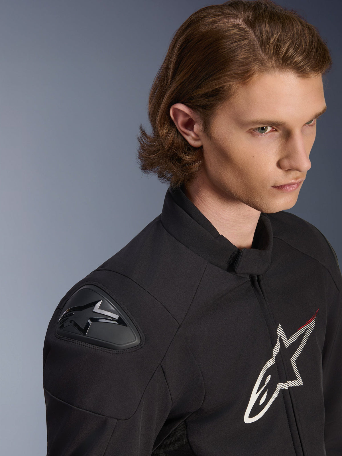 Alpinestars SMX Waterproof Jacket, svart med vita och röda detaljer, närbild på en manlig modell, med externa DFS Lite-axelskydd och en stor stjärnlogotyp på bröstet, sportig motorcykelutrustning