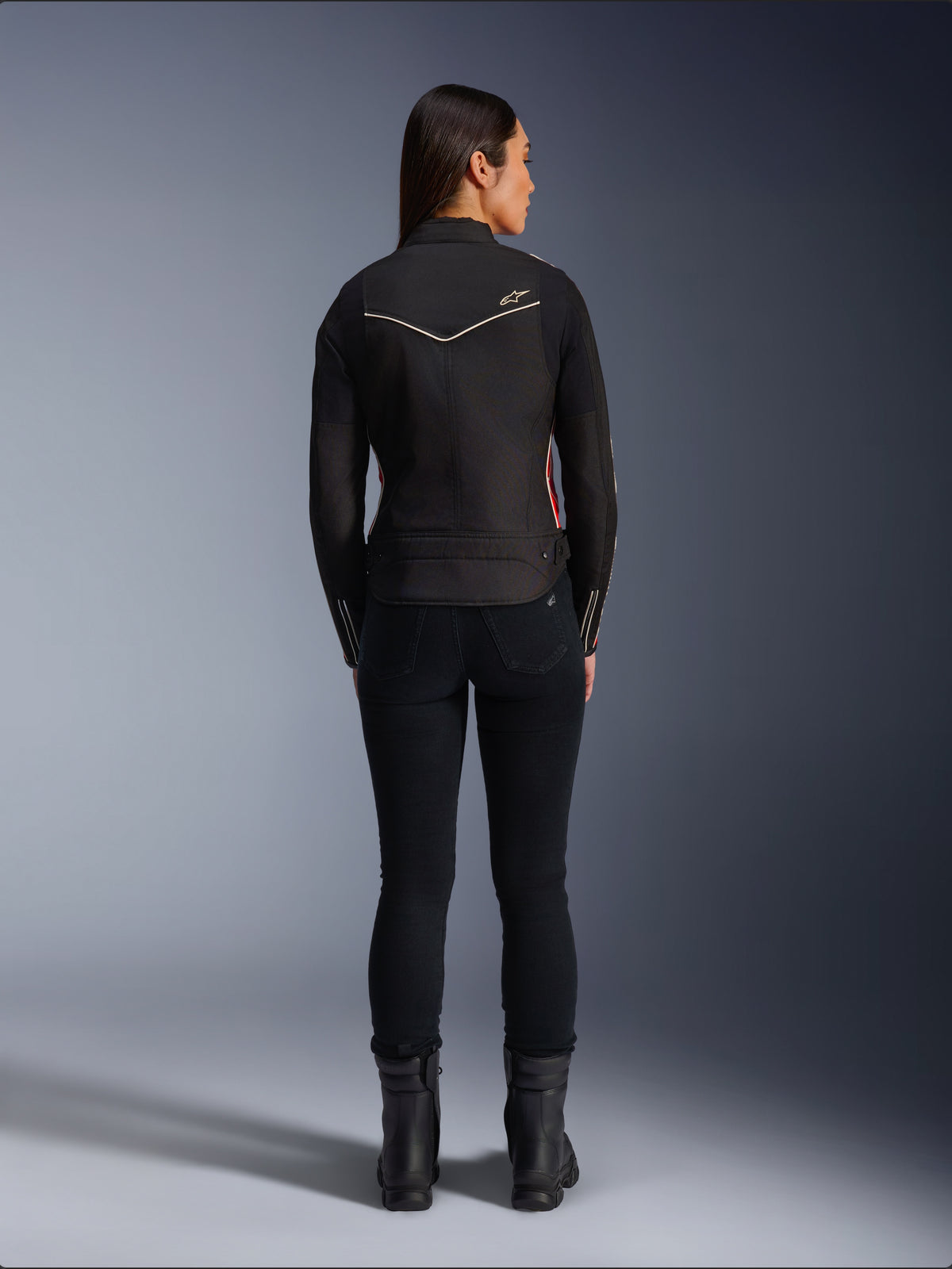 Alpinestars Stella T-Dyno WR-jacka i Black Bright Red Fuchsia, mc-jacka i textil för damer sedd bakifrån, kortare biker-passform, vit stjärnlogotyp på ryggen, stylad med svarta byxor och svarta stövlar