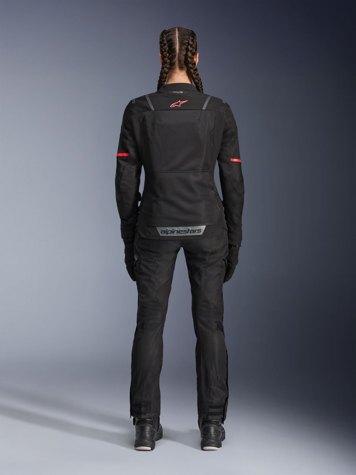 Alpinestars Stella Andes Air Drystar®-byxor, motorcykelbyxor för dam, svarta, vy bakifrån bärs med en matchande meshjacka med röda detaljer, framhäver ventilationspaneler i mesh och reflekterande logotyp på nedre delen av ryggen, designade för äventyr och landsvägstouring.