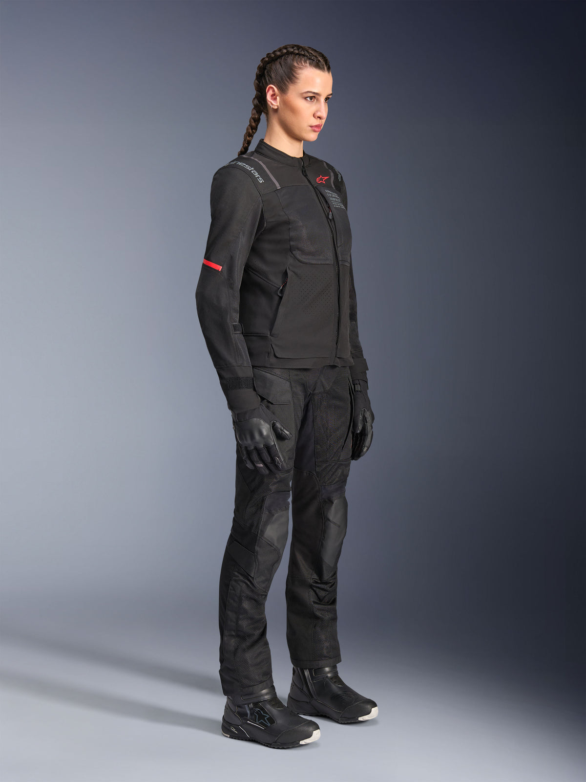 Kvinnlig förare iklädd Alpinestars Stella Andes Air Drystar®-byxor i svart, adventure-textilbyxor med ventilationspaneler i mesh, stylad med matchande Stella-jacka, handskar och stövlar för en komplett touring-outfit för motorcykel.