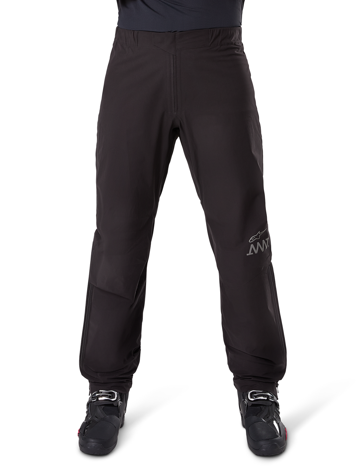 Alpinestars AMT-8 Stretch Drystar® XF byxfoder, svart, sedd framifrån buren med svarta motorcykelstövlar, med grå stjärnlogotyp och AMT-märkning på benet, mångsidiga vattentäta och vindtäta motorcykelkläder