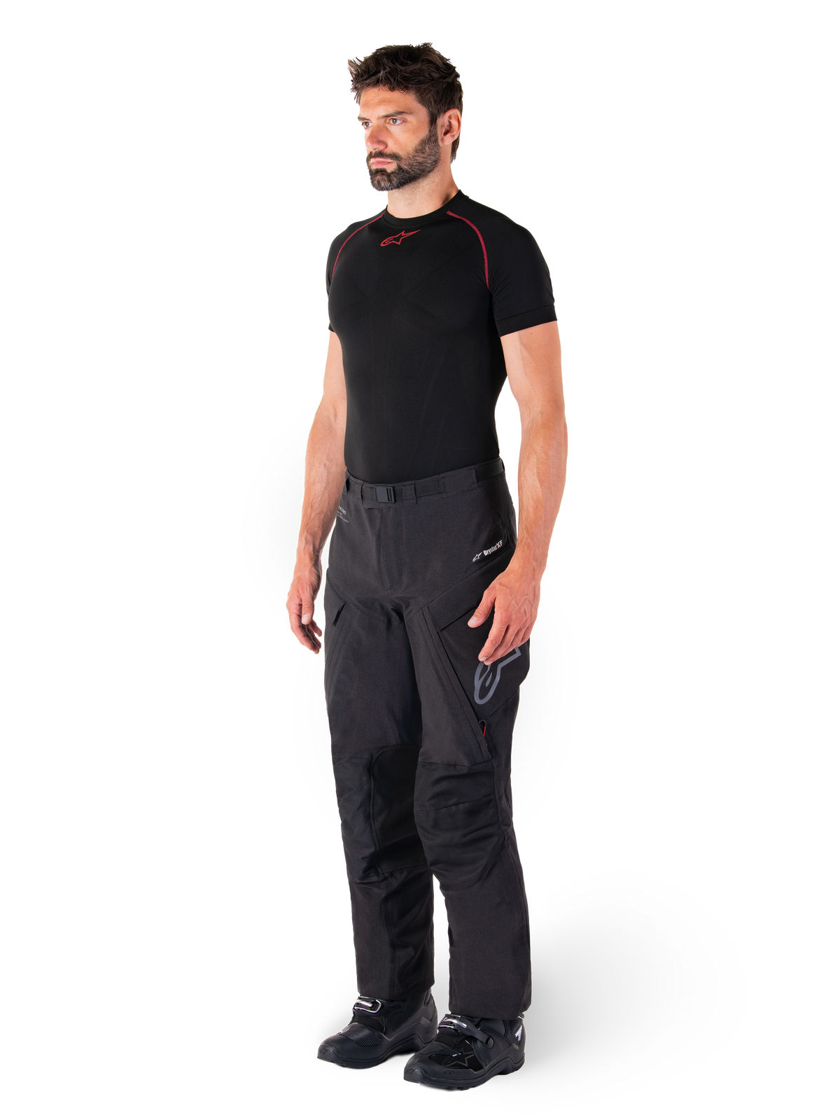 Alpinestars Hyde XT Drystar® Pants, Black adventure touring motorcycle pants worn by a model with a black compression shirt and black boots, featuring technical waterproof construction and Drystar®XF branding.