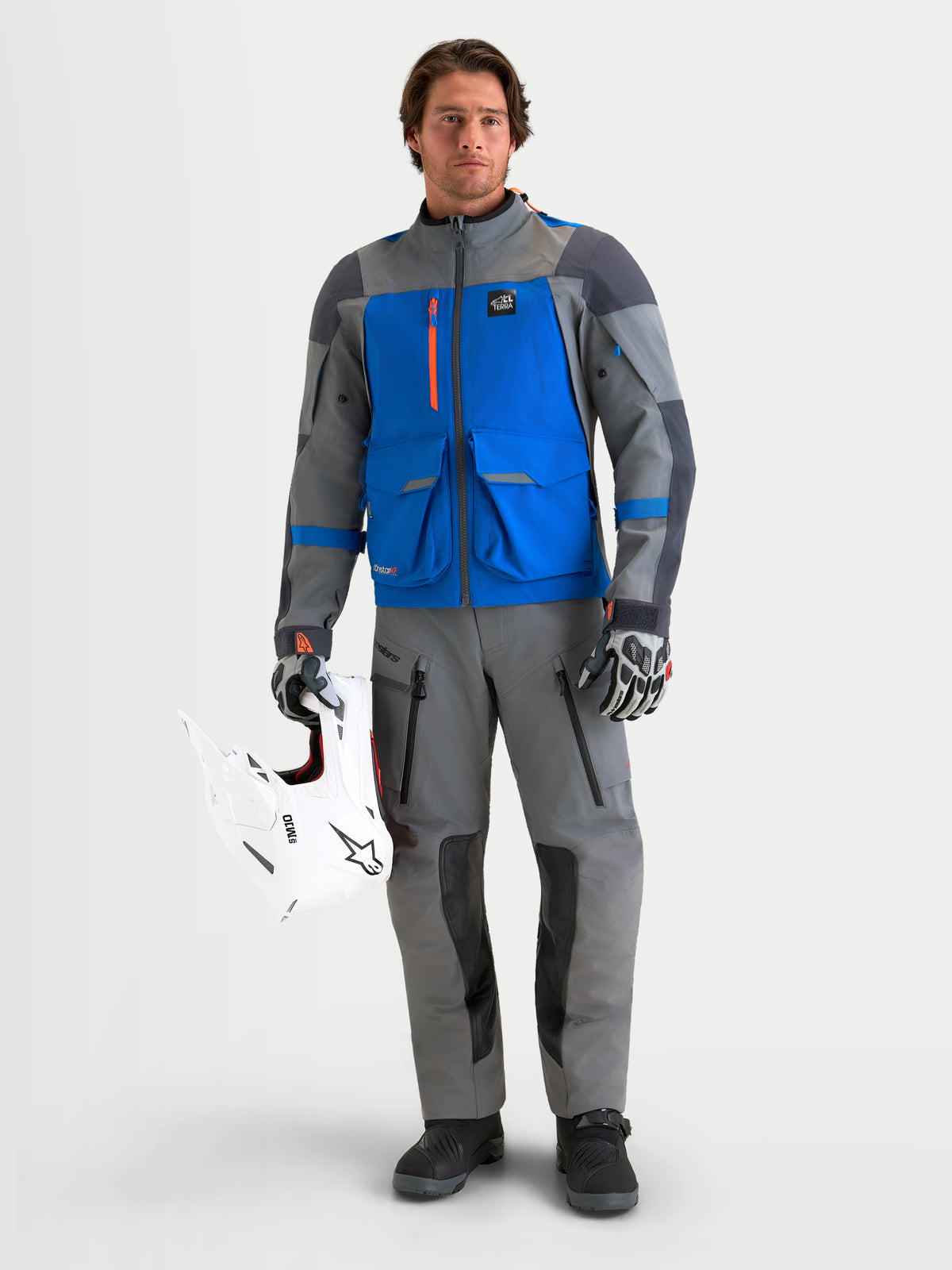 Alpinestars Maxdura Drystar XF Laminated byxor, mörkgrå och svarta äventyrsmotorcykelbyxor för herr med CE-certifierat knäskydd, bärs av en manlig modell som håller i en vit off-road-hjälm