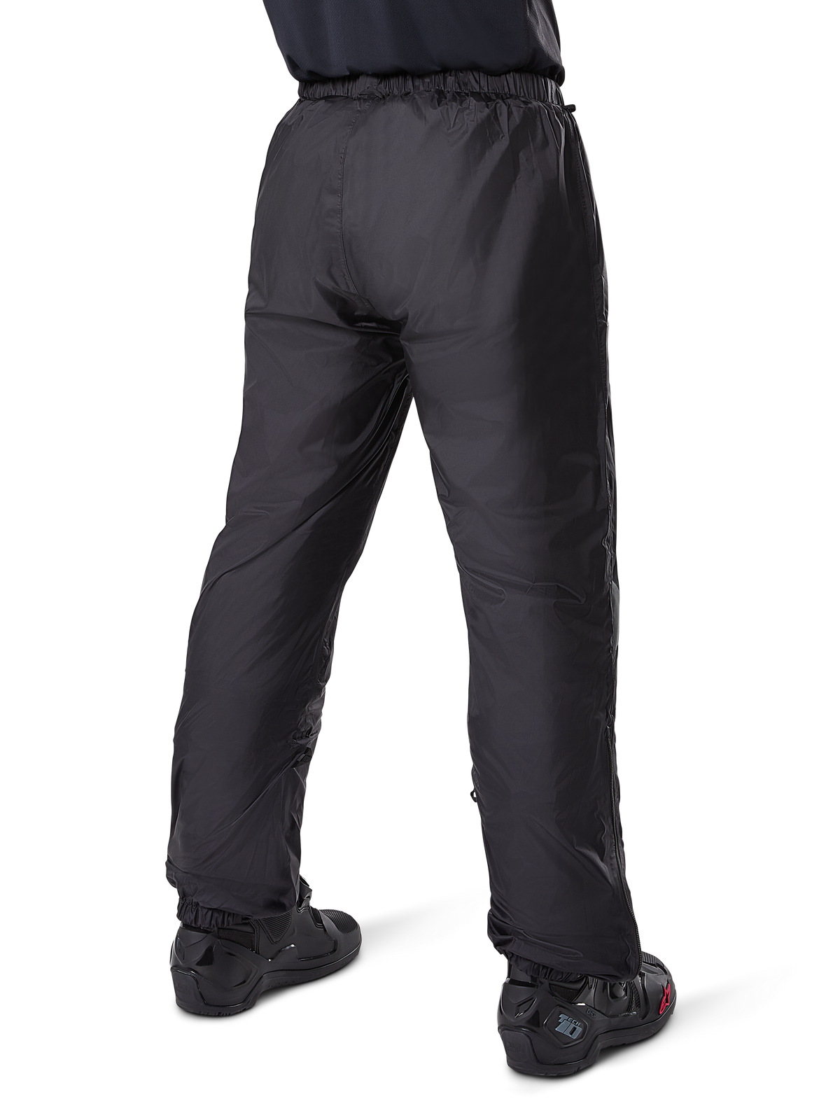 Alpinestars Bogota' Pro Drystar® 3 Seasons-byxor, svarta adventure touring-motorcykelbyxor, bakifrån vy av det vattentäta Drystar®-fodret buret som överdragsbyxor, kombinerat med svarta motorcykelstövlar, teknisk lättviktskonstruktion för väderskydd under flera säsonger