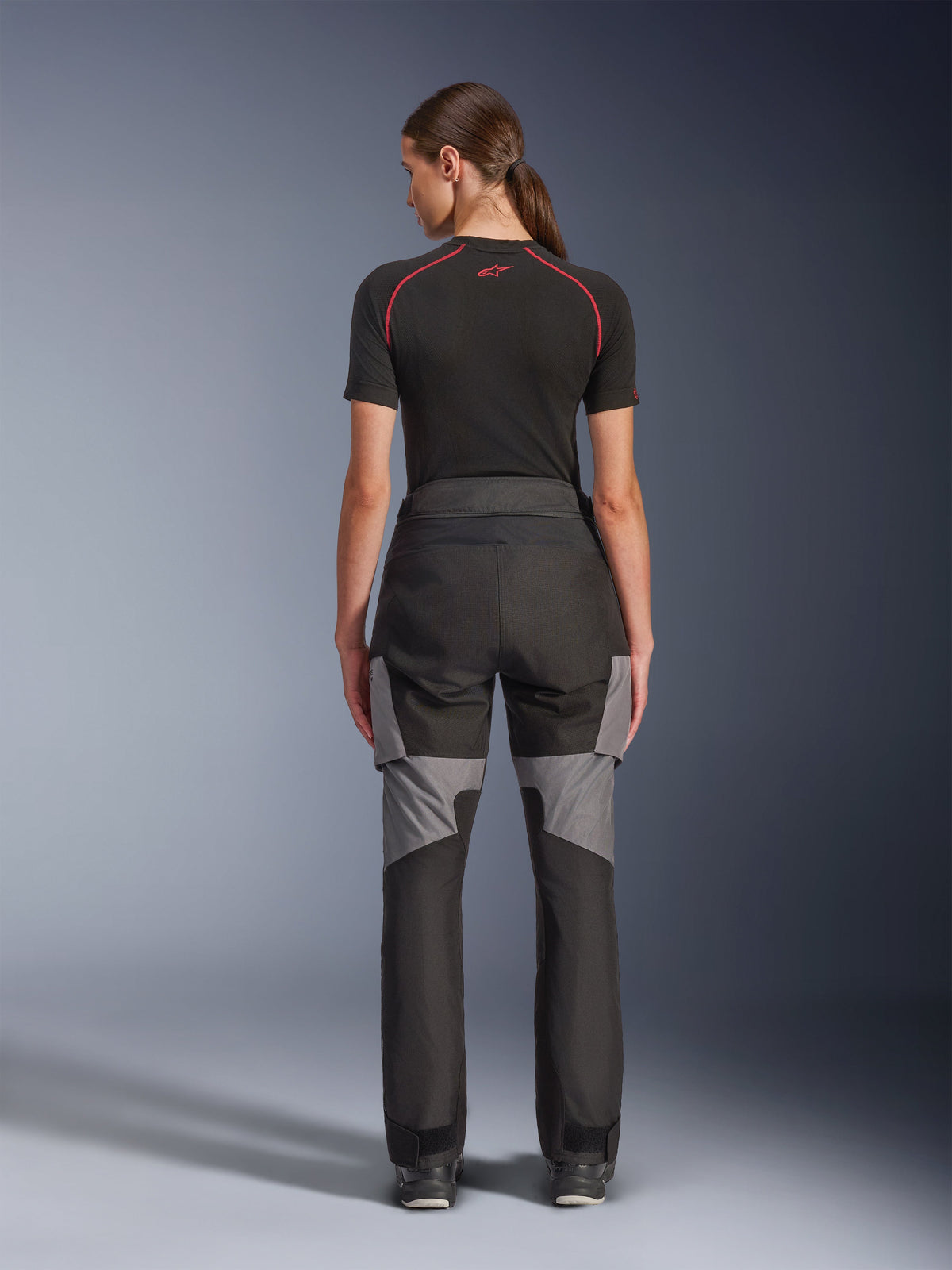 Alpinestars Stella Andes V4 Drystar® byxor, motorcykelbyxor för dam, svarta och mörkgrå, vy bakifrån som visar grå ripstop-förstärkningar och ergonomisk design, bärs med ett svart tekniskt underställ, utrustning för adventure touring