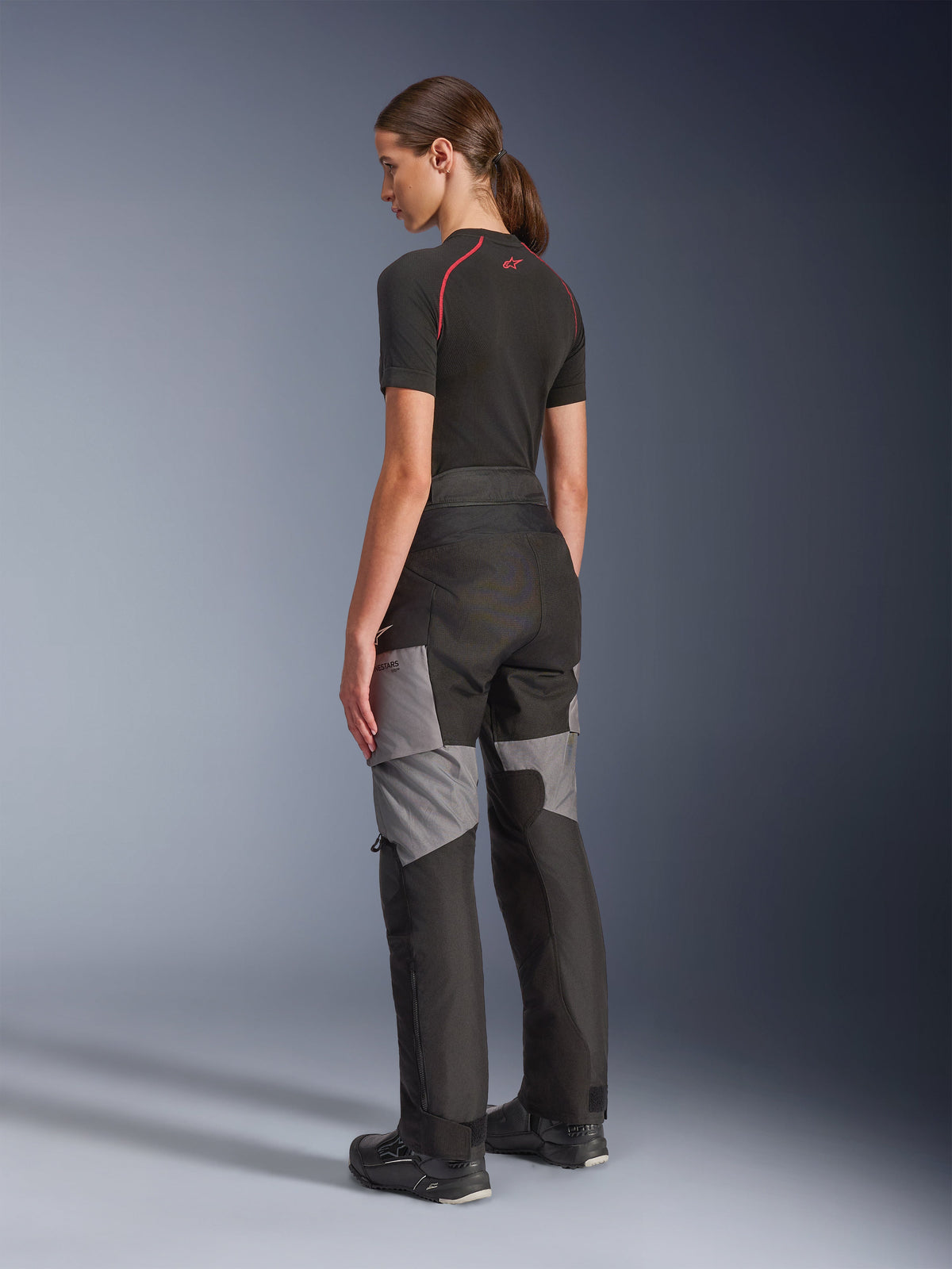 Stella Andes V4 Drystar® byxor för dam, svarta och mörkgrå motorcykelbyxor för äventyrstouring, bak- och sidovy på modell, med hållbar textilkonstruktion, grå förstärkningspaneler och en skräddarsydd passform för kvinnliga förare.
