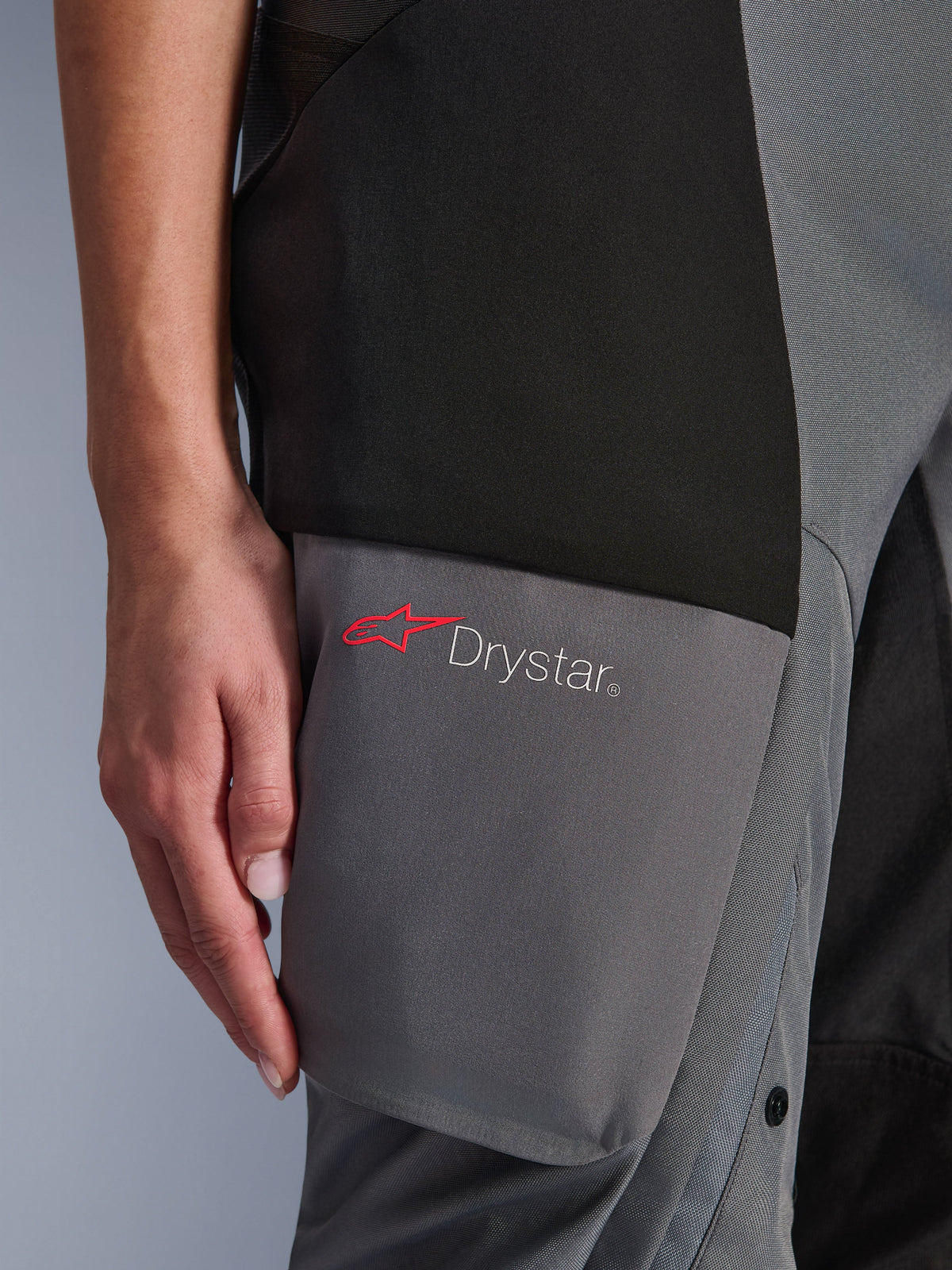 Alpinestars Stella Andes V4 Drystar®-byxor, äventyrs- och touringbyxor för dam, svarta och mörkgrå, detalj av lårområdet som visar Drystar-logotypen och den röda Alpinestars-stjärnan på förstärkta textilpaneler