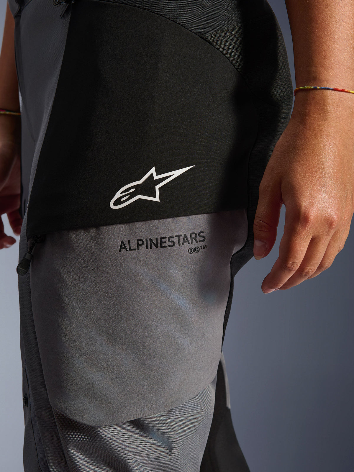 Stella Andes V4 Drystar® dambyxor, svarta och mörkgrå, närbild på övre låret som visar vit stjärnlogotyp och svart Alpinestars-logotyp, hållbart textilmaterial för adventure touring