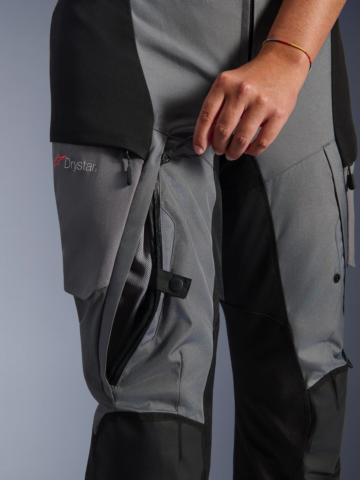Alpinestars Stella Andes V4 Drystar byxor, svart och mörkgrå textil, närbild på direkt ventilationsdragkedja på låret som öppnas för hand, meshfoder synligt, Drystar-logotyp, äventyrsutrustning för motorcykelåkning