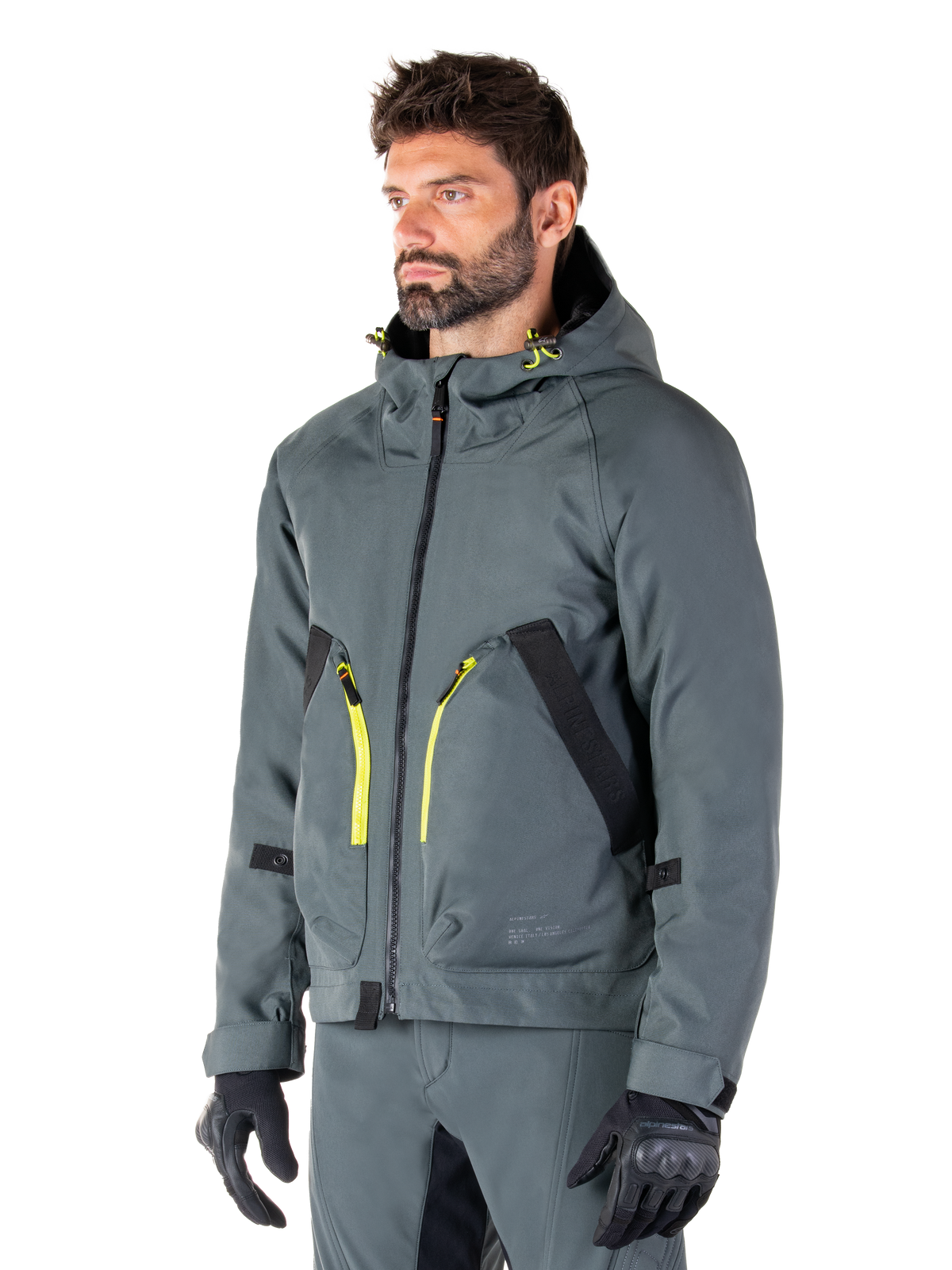 Alpinestars Morush Waterproof Parka, Urban Gray motorcykeljacka, design med huva och klargula dragkedjeaccenter, svarta fickdetaljer, bärs med matchande grå körbyxor och svarta handskar, samtida streetwear-inspirerad motorcykelklädsel.