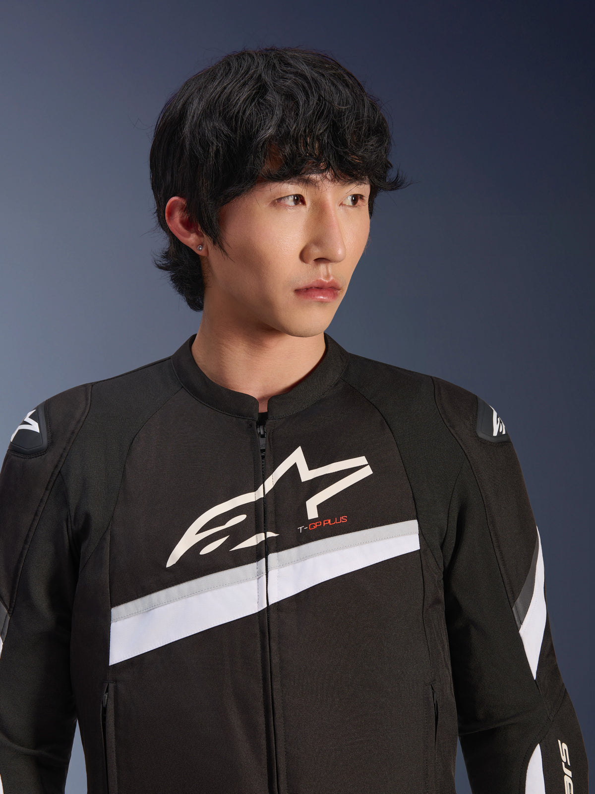 Alpinestars T-GP Plus R V4 Jacket, Black and White, textile motorcycle jacket worn by a male model, featuring a large white star logo on the chest, white diagonal stripes, and DFS Lite shoulder protectors, sport-inspired street riding gear.
