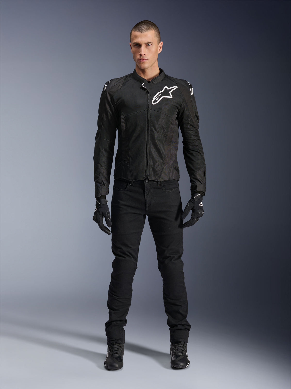 Alpinestars Viper Air V4-jacka, svart motorcykeljacka i textil, vit logotyp på bröstet och axlarna, bärs med svarta MC-byxor och handskar, har tekniska meshpaneler för luftflöde, helkroppsbild i studiomiljö.