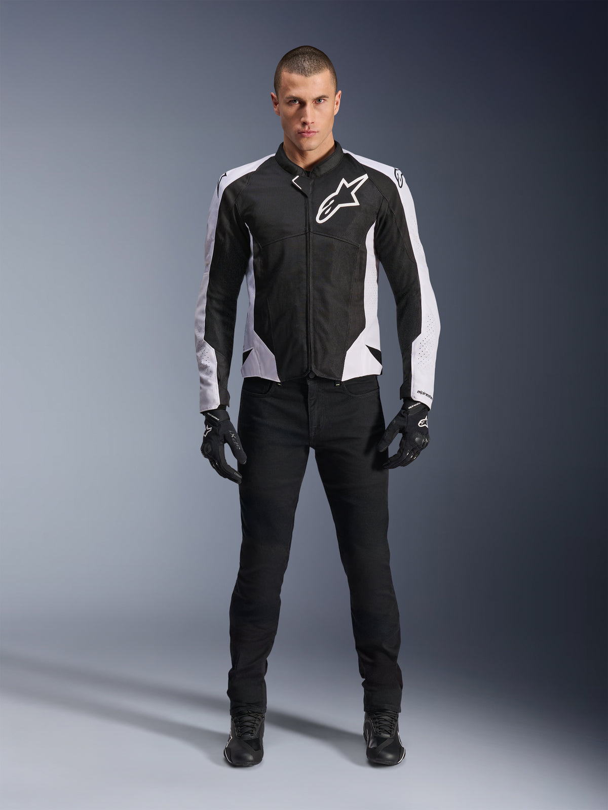 Alpinestars Viper Air V4-jacka, svart och vit motorcykeljacka med stor vit logotyp på bröstet, bärs av en manlig modell med svarta byxor och handskar, med meshpaneler för ventilation, sportig mc-utrustning för vägkörning