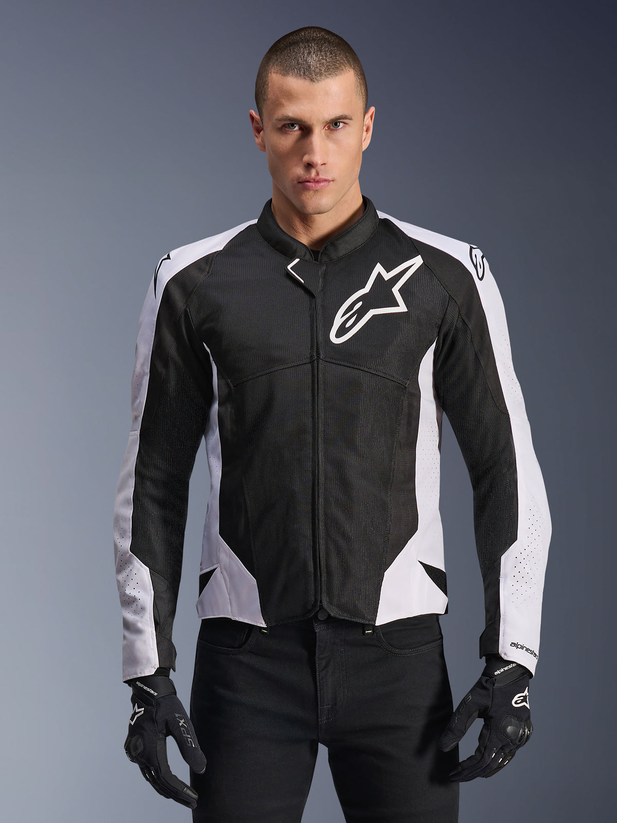 Alpinestars Viper Air V4-jacka, motorcykeljacka för racing, svart och vit, buren av förare, teknisk mesh- och textilkonstruktion med vita axelpaneler, tydlig stjärnlogotyp på bröstet, sportig prestandadesign, kombinerad med svarta körhandskar