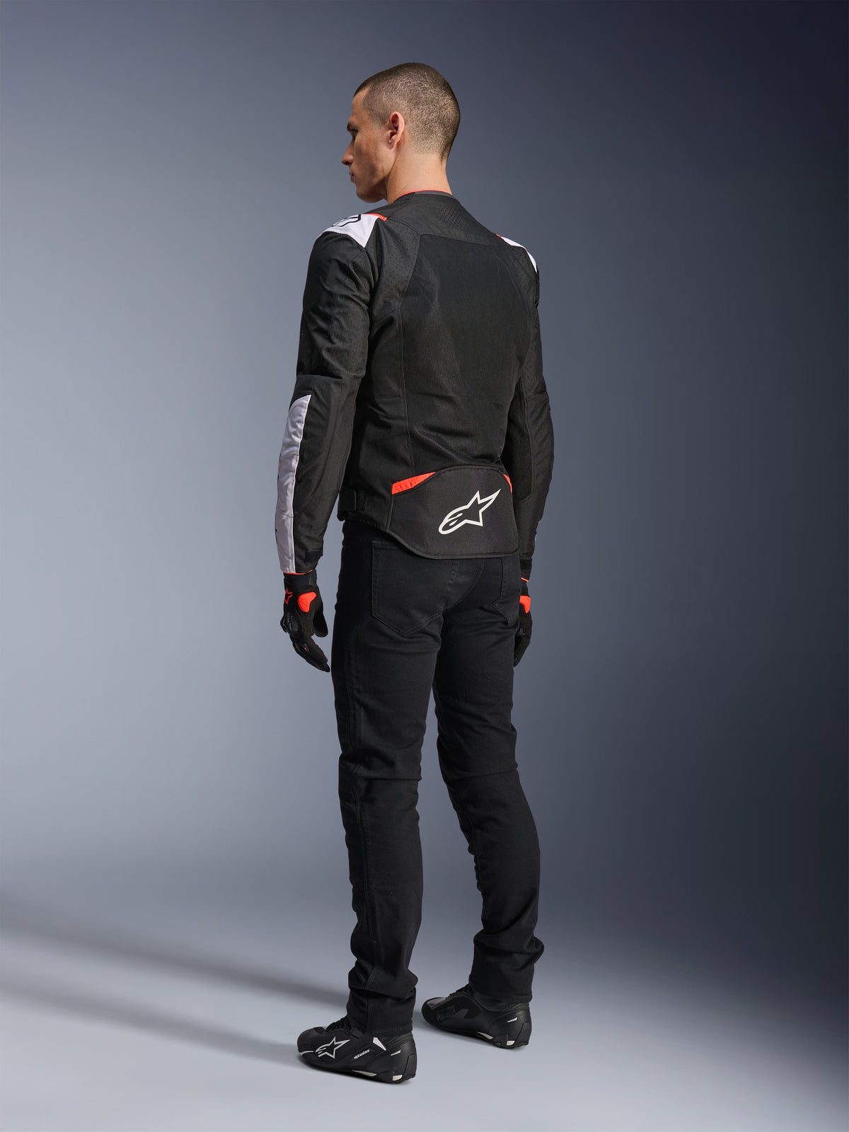 Alpinestars T-Sps Air V2 Jacket, Textile Motorcycle Jacket, Black White and Red Fluo, rear view on model, mesh paneling for ventilation, white Astars logo on lower back, styled with black riding pants and gloves