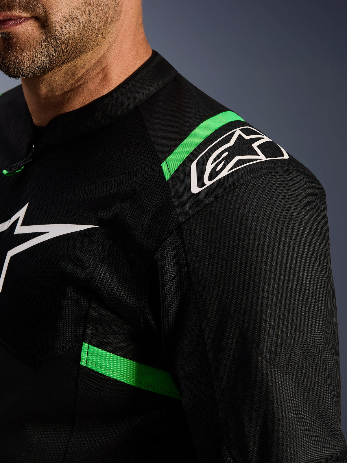 Alpinestars T-SPS Air V2 Jacket, Black and Fluo Green, close-up of shoulder and chest area, white Alpinestars star logo, technical mesh fabric for airflow, sporty motorcycle riding jacket