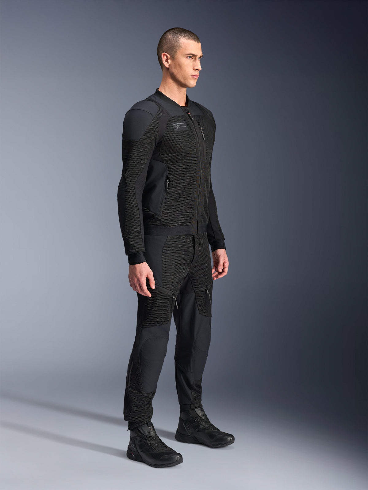 Alpinestars Troop-Air Pro-jacka, teknisk bepansrad ventilerad jacka, svart, bärs av modell med matchande svarta motorcykelbyxor och stövlar, med avancerad 2D-tech mesh-struktur och ventilerande paneler, urban samtida körutrustning.