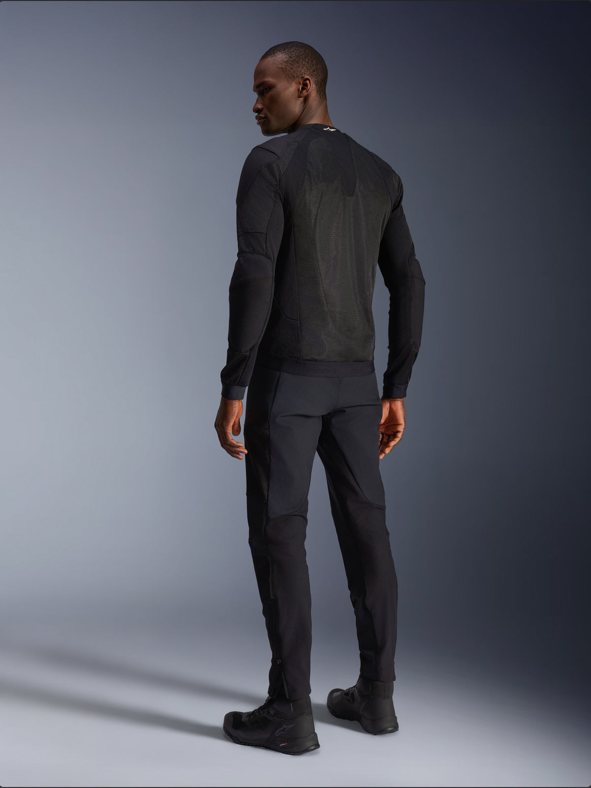 Alpinestars Troop-Air jacka, svart urban motorcykeljacka, vy bakifrån på modell med stora meshpaneler för maximal ventilation och komfort under sommarkörning.