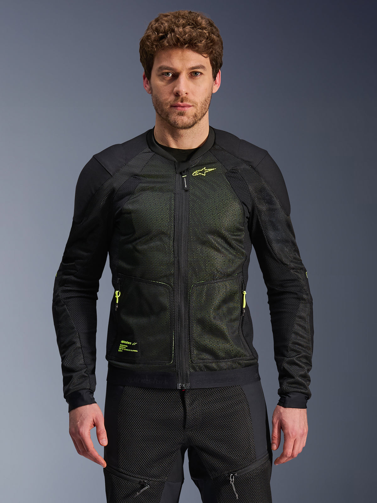 Alpinestars Troop-Air-jacka, svart och neongul, bärs av en manlig modell, lätt mesh-konstruktion, neongula dragkedjor och logotyper, teknisk ventilerad motorcykeljacka för stadskörning