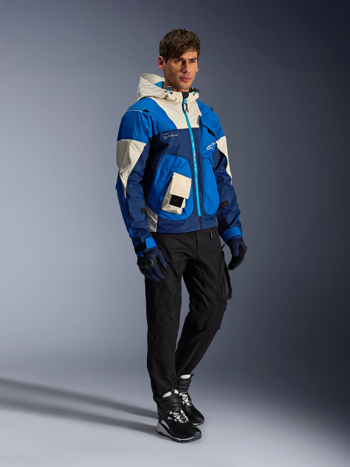 Alpinestars Mogress Air jacka, blå och vit urban motorcykeljacka för herrar med huva, bärs av modell med svarta MC-byxor.