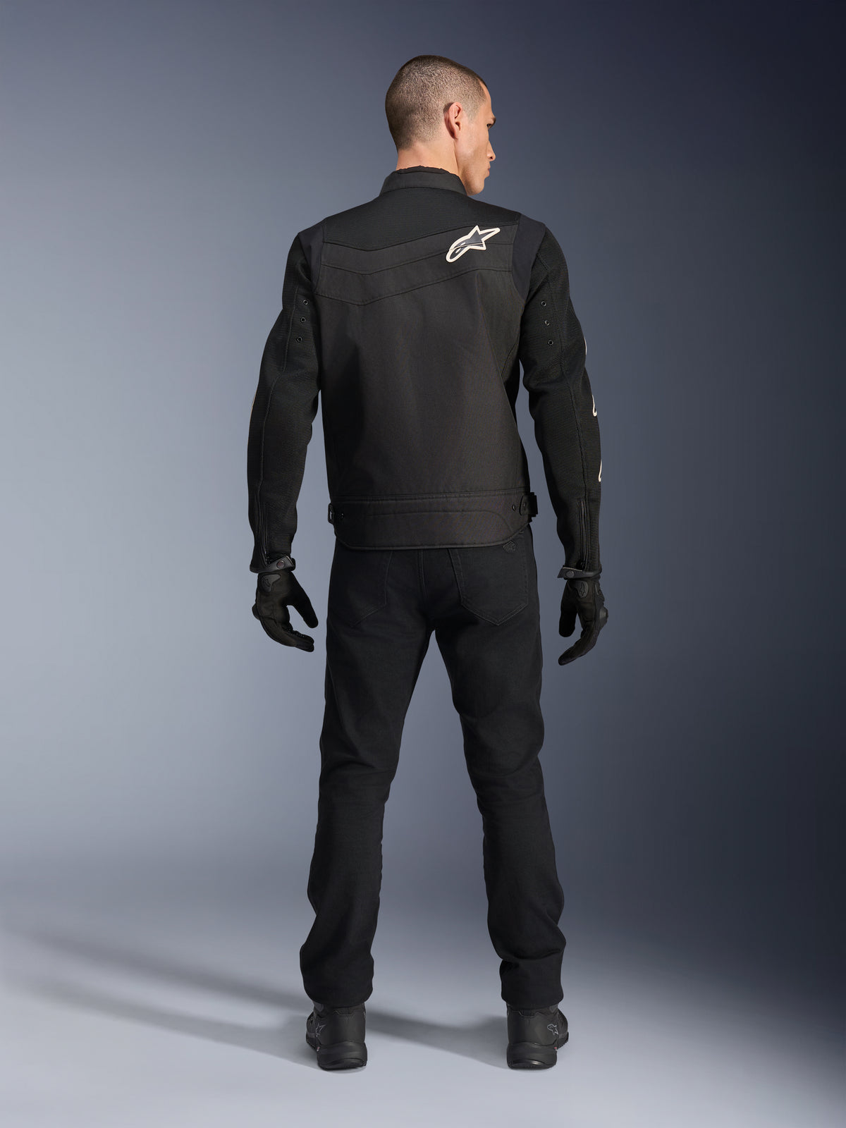 Alpinestars T-Dyno Air Jacket, Black, Rear view on model, Textile motorcycle jacket featuring 3D mesh panels and a white star logo on the shoulder, worn with black pants and gloves, modern urban riding outfit