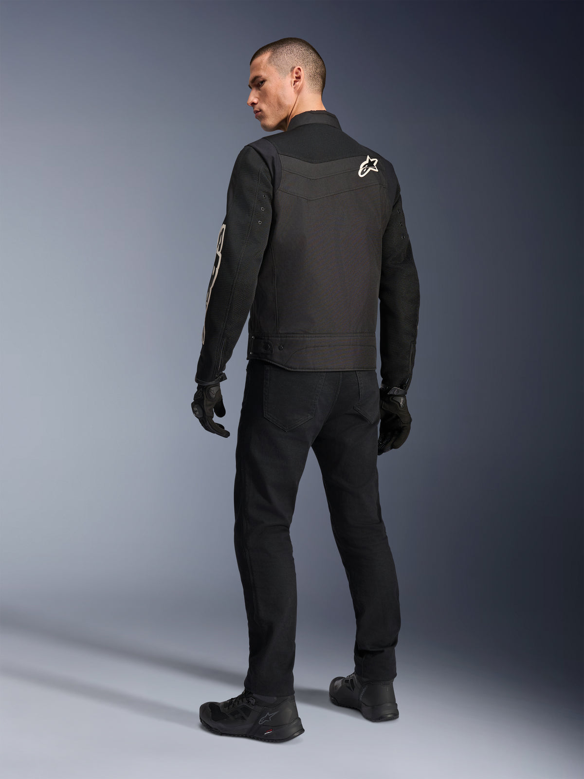 Alpinestars T-Dyno Air Jacket, Black, Back view of model wearing a breathable textile motorcycle jacket, featuring white Alpinestars logo on the shoulder, paired with black pants and gloves, urban riding style