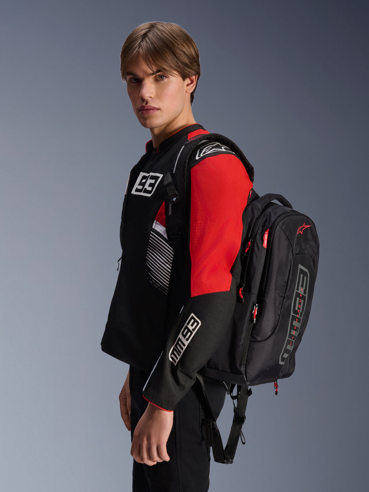 Alpinestars MM93 City Hunter V2 ryggsäck, svart med röda detaljer, bärs av en modell i en matchande svart och röd MM93 motorcykeljacka, med Marc Márquez-branding och logotyper, urban körutrustning