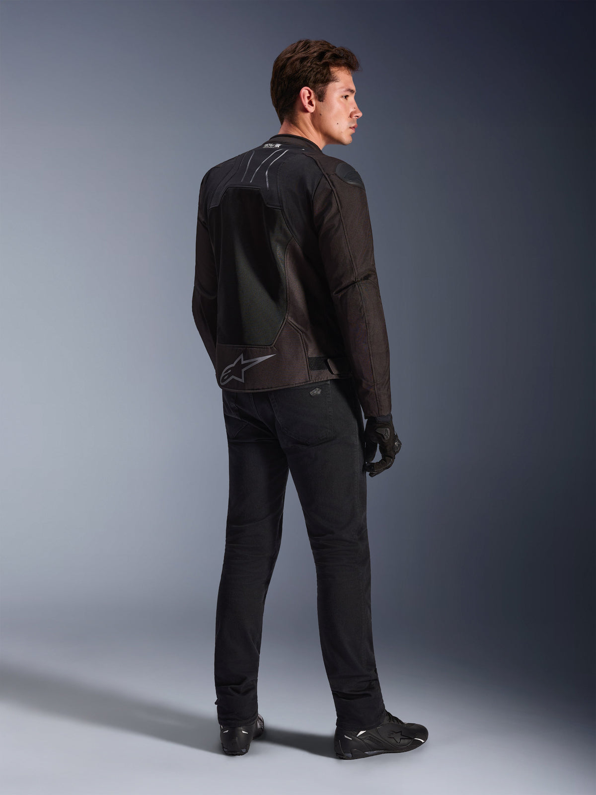 Alpinestars SMX Air-jacka i Black Anthracite, vy bakifrån på modell, med Tech-Air® Ready-branding på kragen och Astar-logotyp på nedre delen av ryggen, buren med svarta mc-byxor och skor.