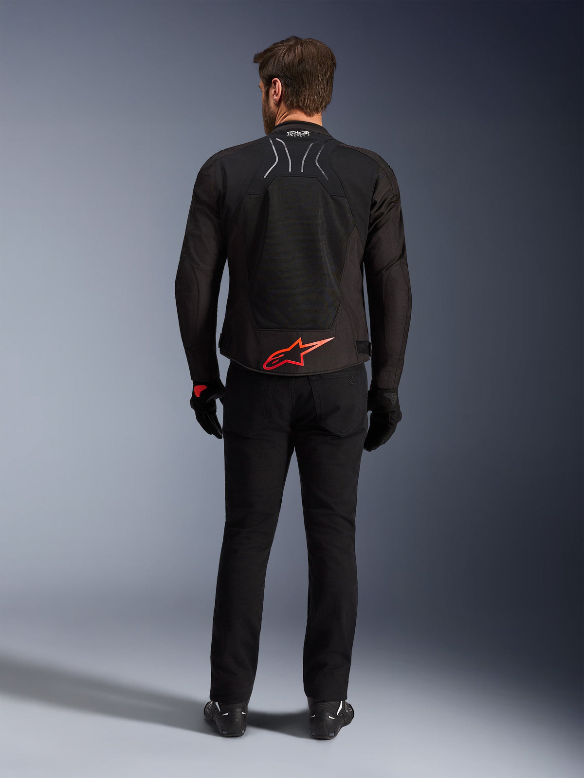 Alpinestars SMX Air-jacka, svart med klarröd logotyp, vy bakifrån som visar Tech-Air Ready-märkning och ventilationspaneler i mesh, bärs med svarta byxor och handskar, högpresterande sport- och racingutrustning för motorcykel