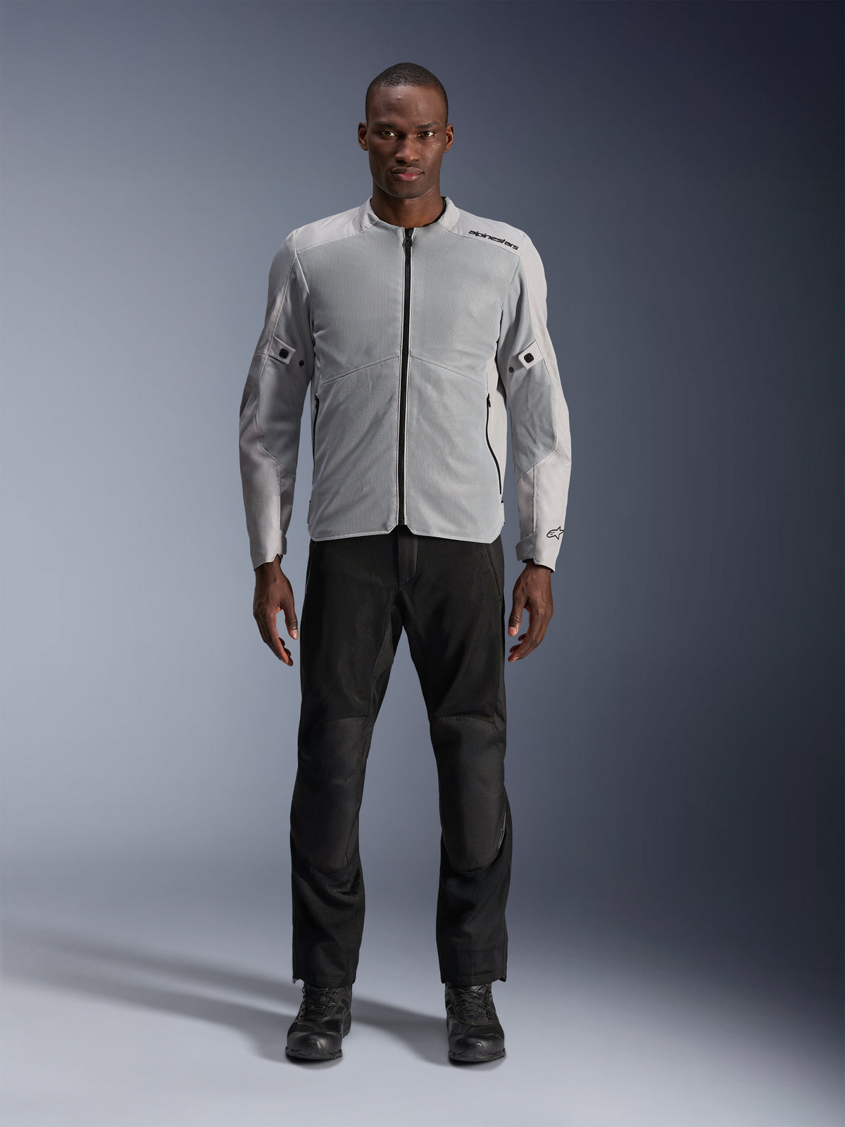 Alpinestars C-1 Air-jacka i silver, urban textilmotorcykeljacka för herrar med ventilerade meshpaneler, bärs av en modell med svarta mc-byxor och svarta stövlar, modern pendlingsstil