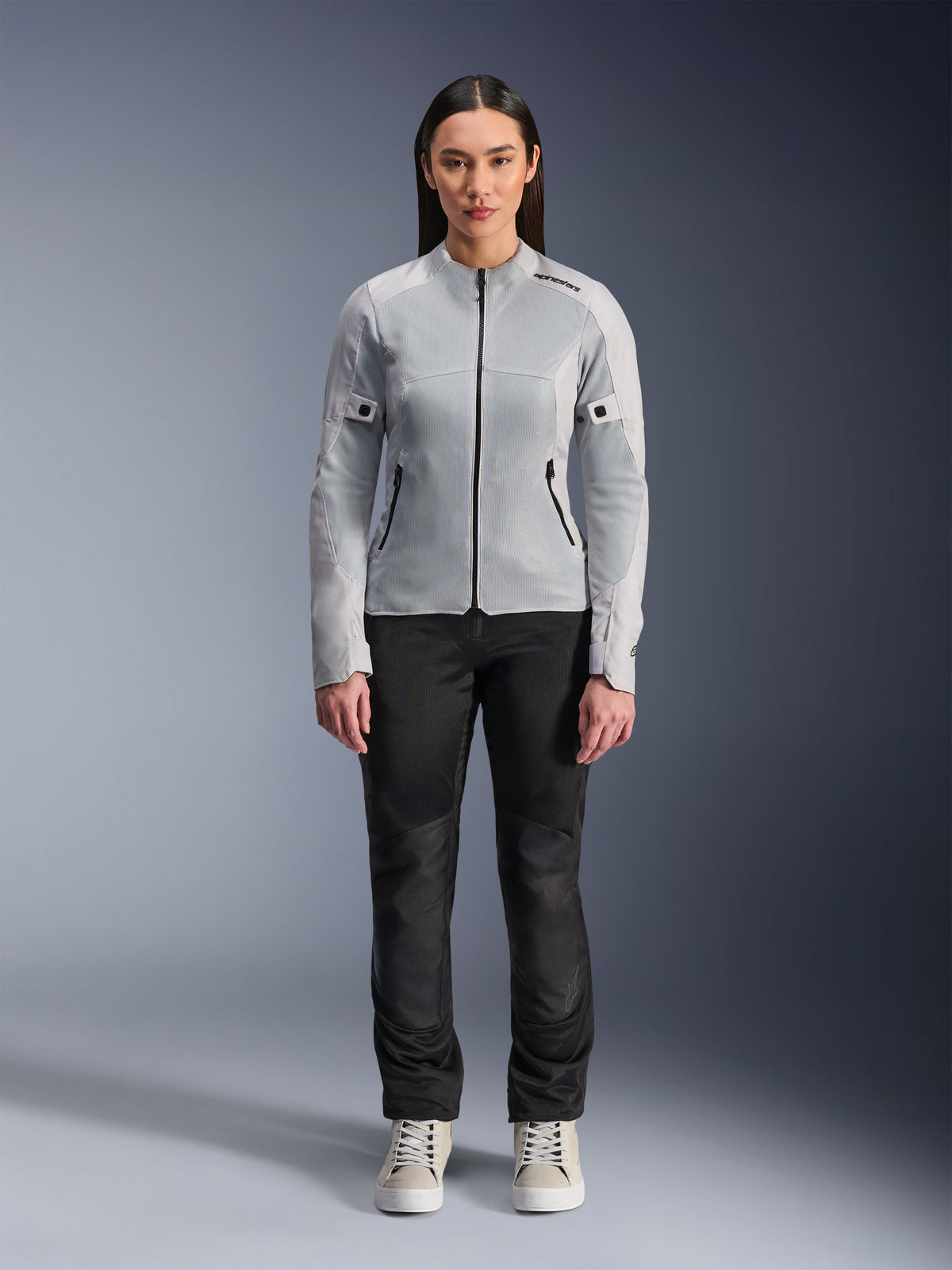 Woman wearing Alpinestars Stella C-1 Air Jacket in Silver, front view, urban motorcycle textile jacket with tech mesh panels, styled with black pants and white sneakers, contemporary riding gear