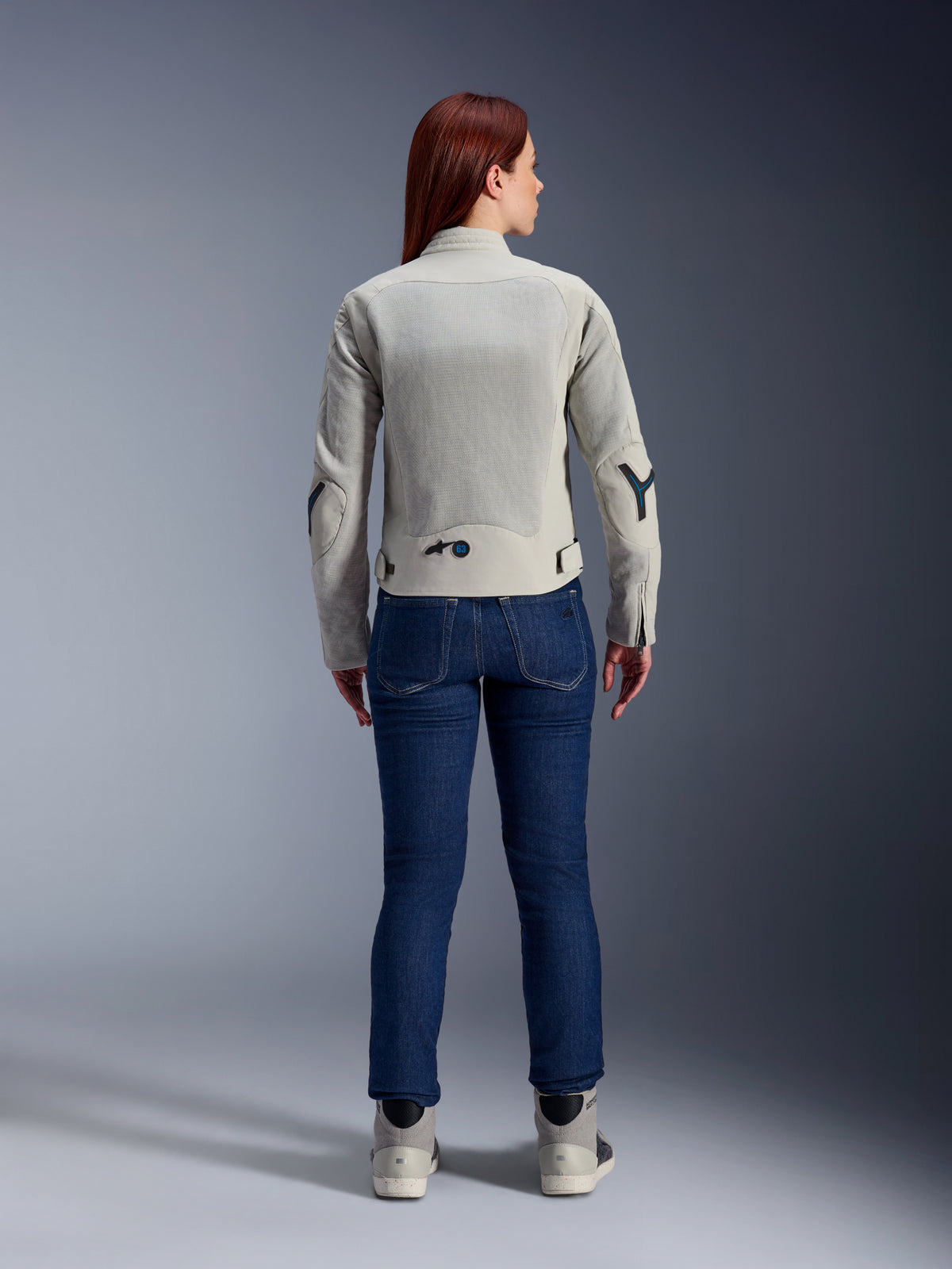Alpinestars Stella Circal-1 Air-jacka för damer i färgerna Metal Gray och Methyl Blue, sedd bakifrån, med stora meshpaneler för luftflöde på ryggen och ärmarna, buren med mörkblå denimjeans och grå körskor för en modern urban motorcykelstil.