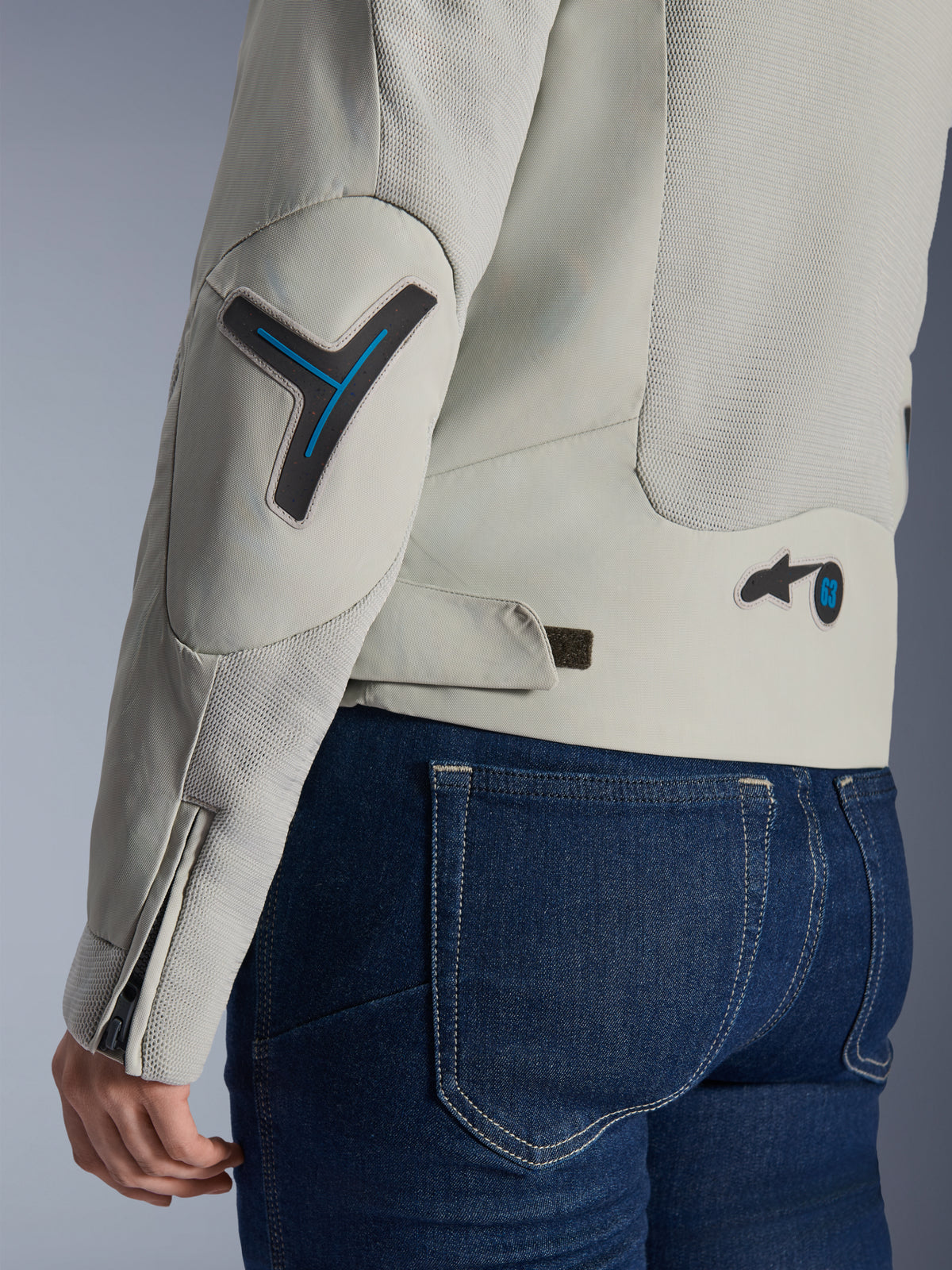 Alpinestars Stella Circal-1 Air-jacka för dam i Metal Gray och Methyl Blue, närbild på rygg- och ärmdetaljer som visar meshpaneler för luftflöde, neonblå accenter på armbåge och midja samt en justerbar flik, bärs med mörkblå denimjeans.