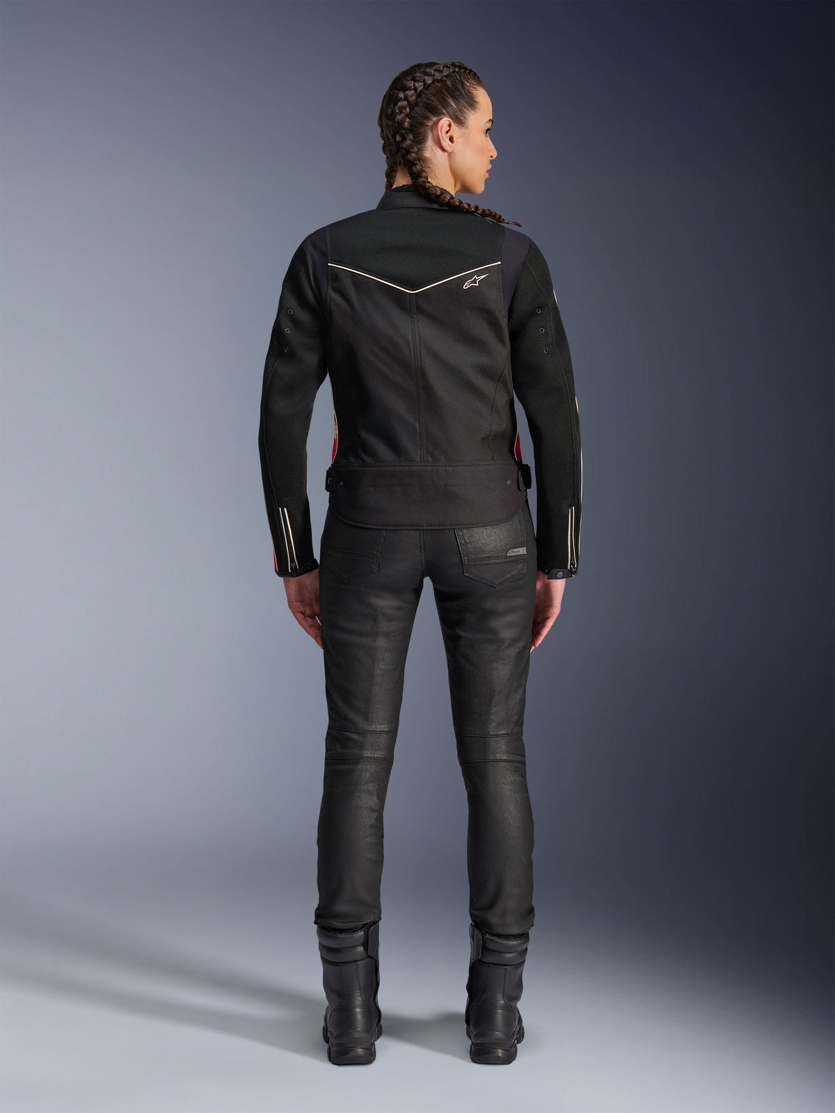 Alpinestars Stella T-Dyno Air-jacka, vy bakifrån, svart motorcykeljacka för dam med vita passpoaler och liten stjärnlogotyp, bärs med svarta tekniska byxor och mc-stövlar, smidig biker-passform för urban stadskörning