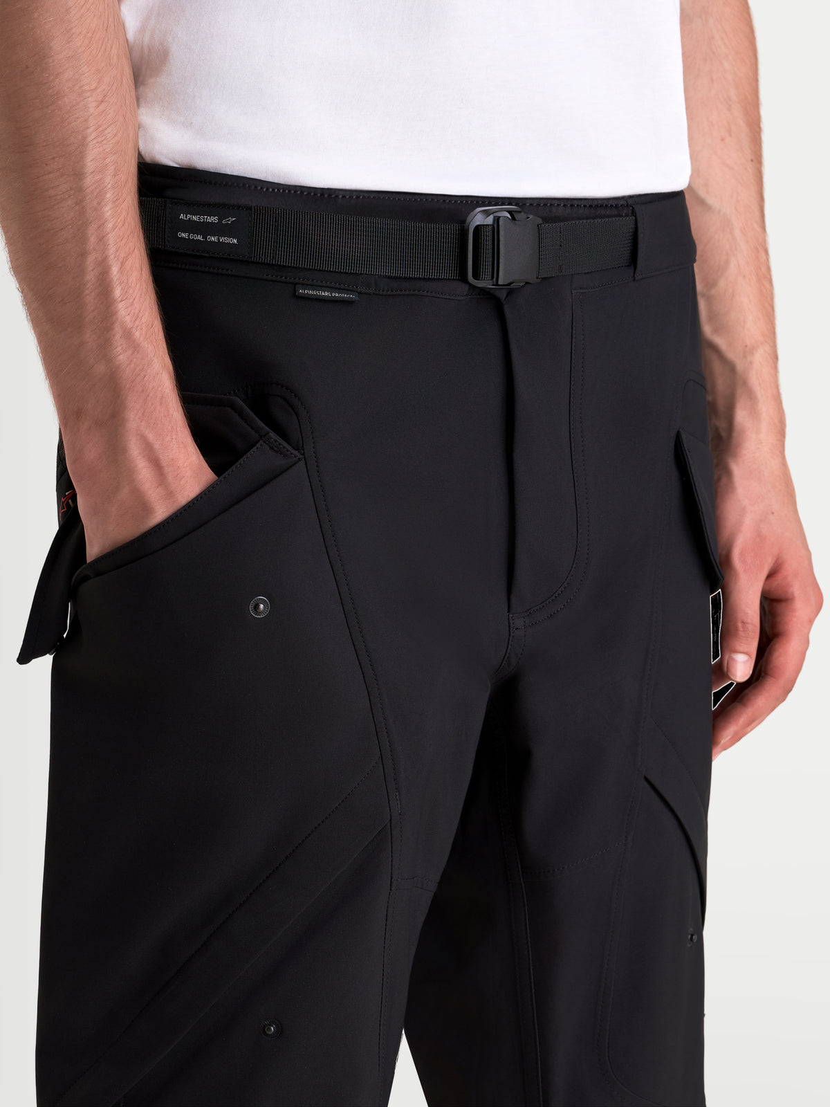 Alpinestars Juggernaut V2 Drystar byxor, svarta urbana motorcykelbyxor, närbild som visar det justerbara bältet, magnetspännet och frontfickorna på en modell