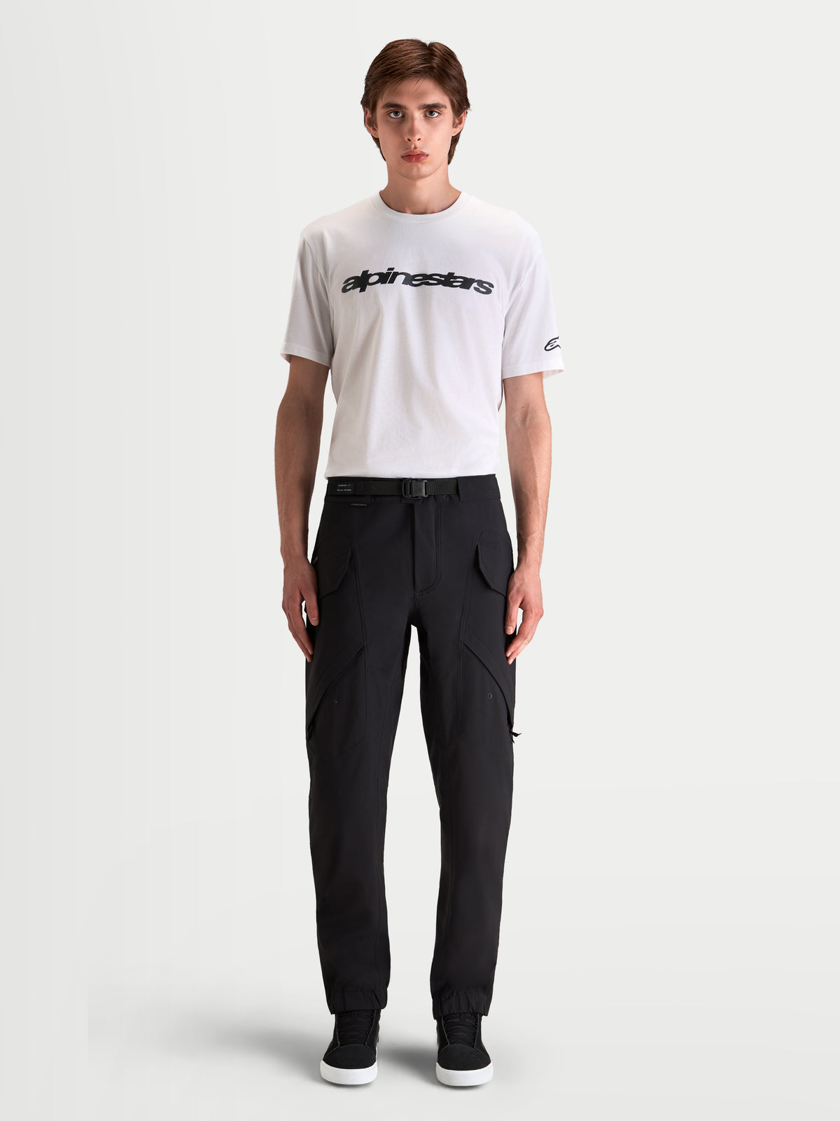 Alpinestars Juggernaut V2 Drystar byxor, svarta vattentäta mc-byxor för urban körning för herr, framifrån på modell med vit t-shirt och lediga körstövlar, med cargofickor och justerbar midja med bälte