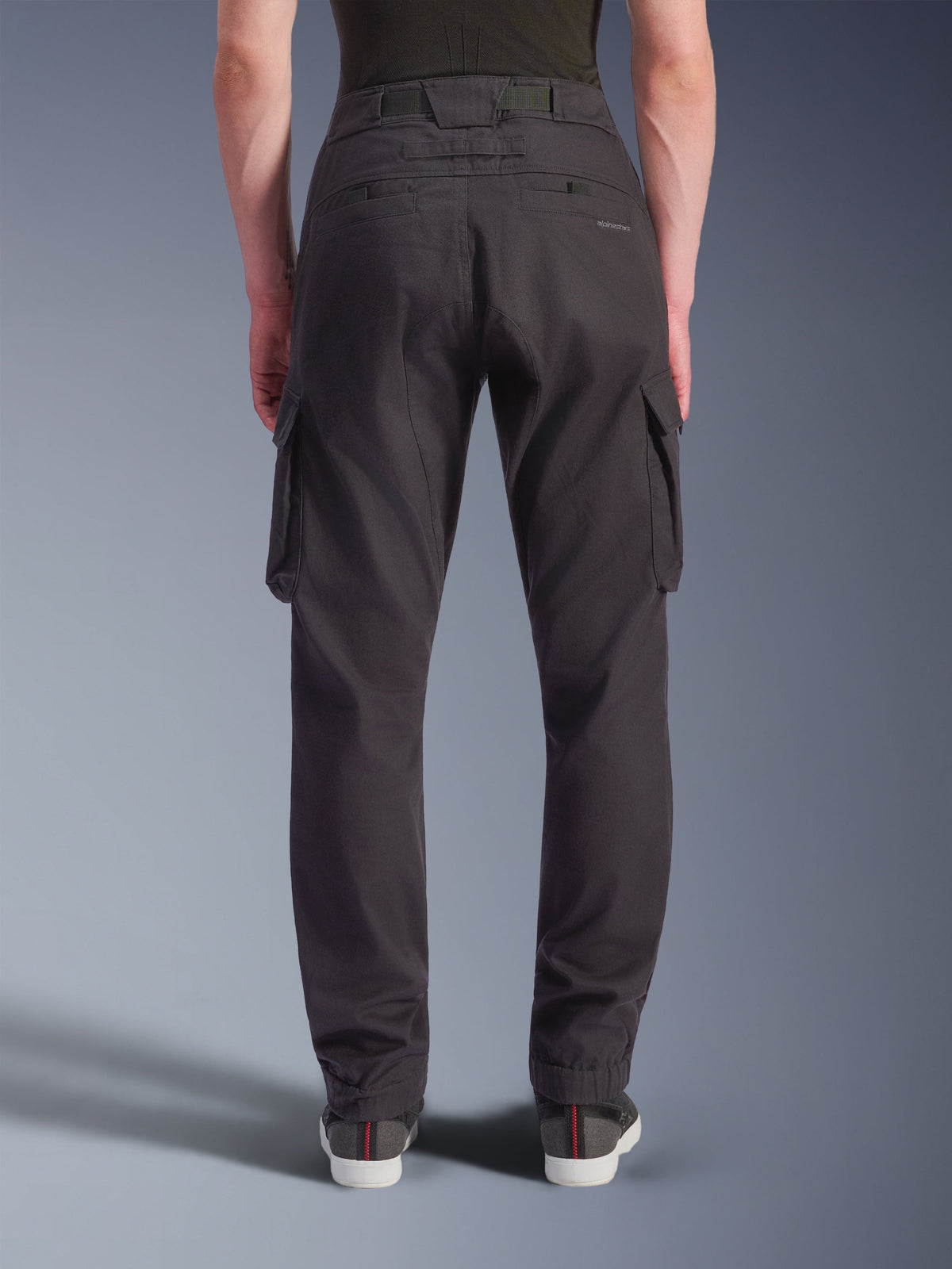 Alpinestars Flex-AST Cargo Pants - Short, Urban Motorcycle Pants, Black, back view showing a regular tapered fit with elasticated hems, large side cargo pockets, and subtle branding on the back pocket, worn with casual sneakers