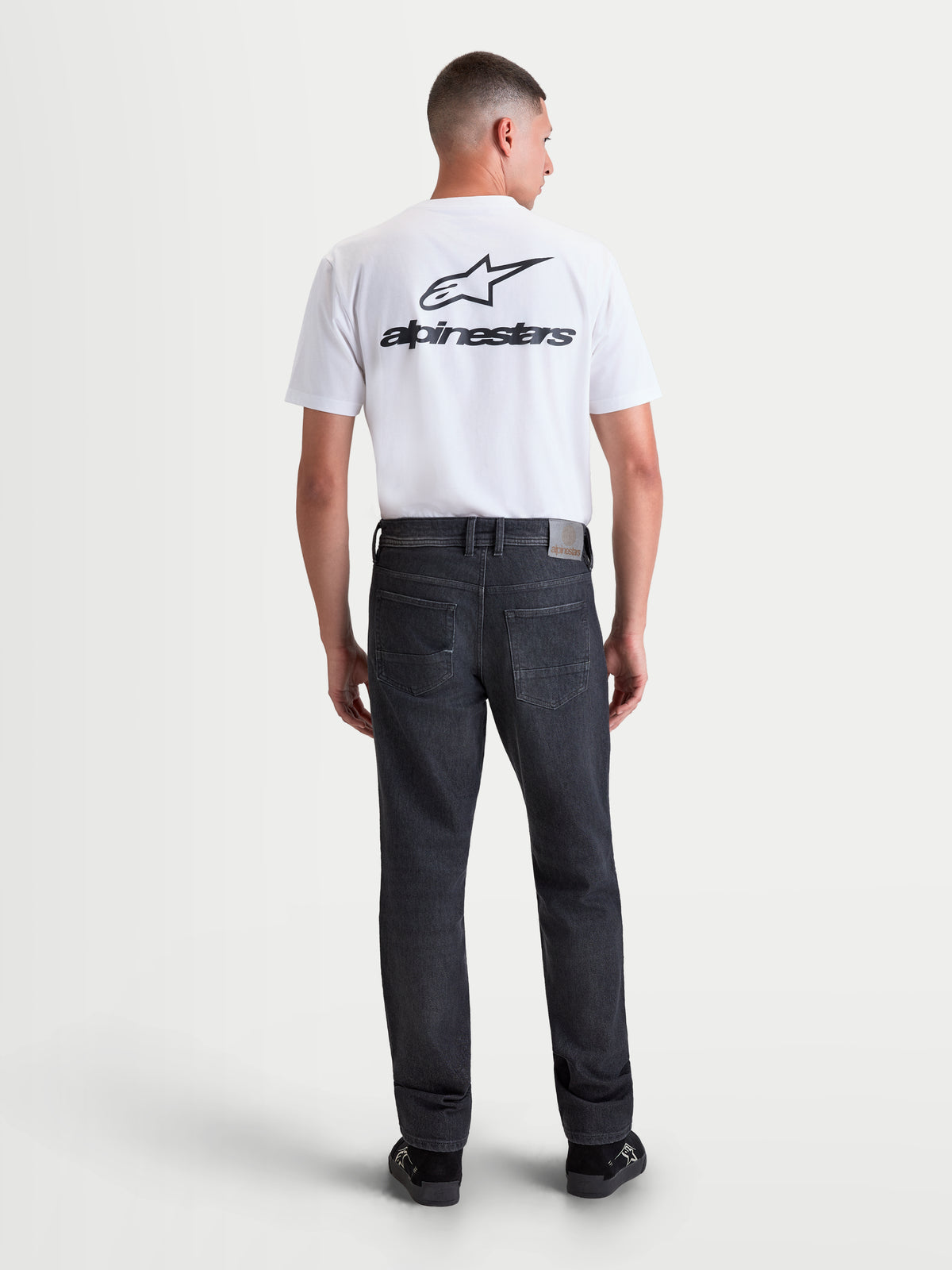Alpinestars Flex Ast 8 Denim byxor, svarta motorcykeljeans för herr, vy bakifrån på modell som visar AA-certifierat enfärgat denimtyg med läderdetalj och bakfickor