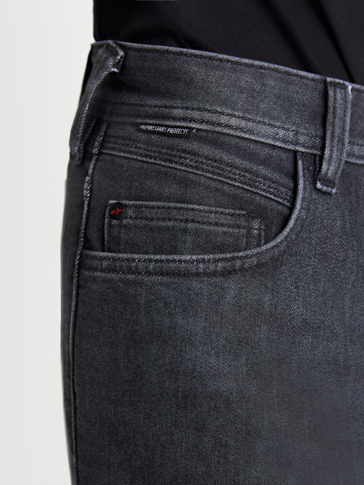 Alpinestars Flex Ast 7 denimbyxor, urtvättade svarta motorcykeljeans för urban körning, närbild som visar fickkonstruktion, märkesdetalj med nit och vävd Alpinestars Protects-etikett