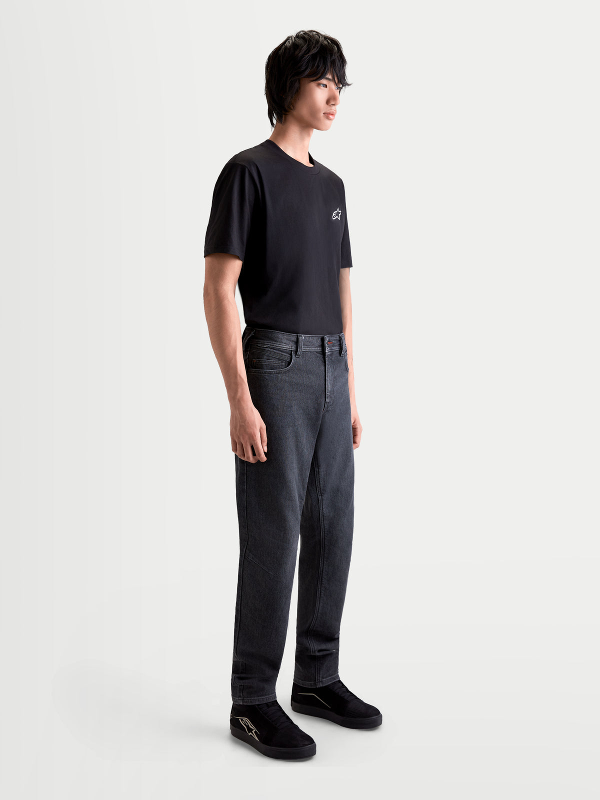 Alpinestars Flex Ast 7 Denim byxor, urban samtida motorcykeljeans för herr i urtvättad svart, sidovy på en modell som bär en svart t-shirt och skor, AA-certifierad enlagers konstruktion av teknisk denim
