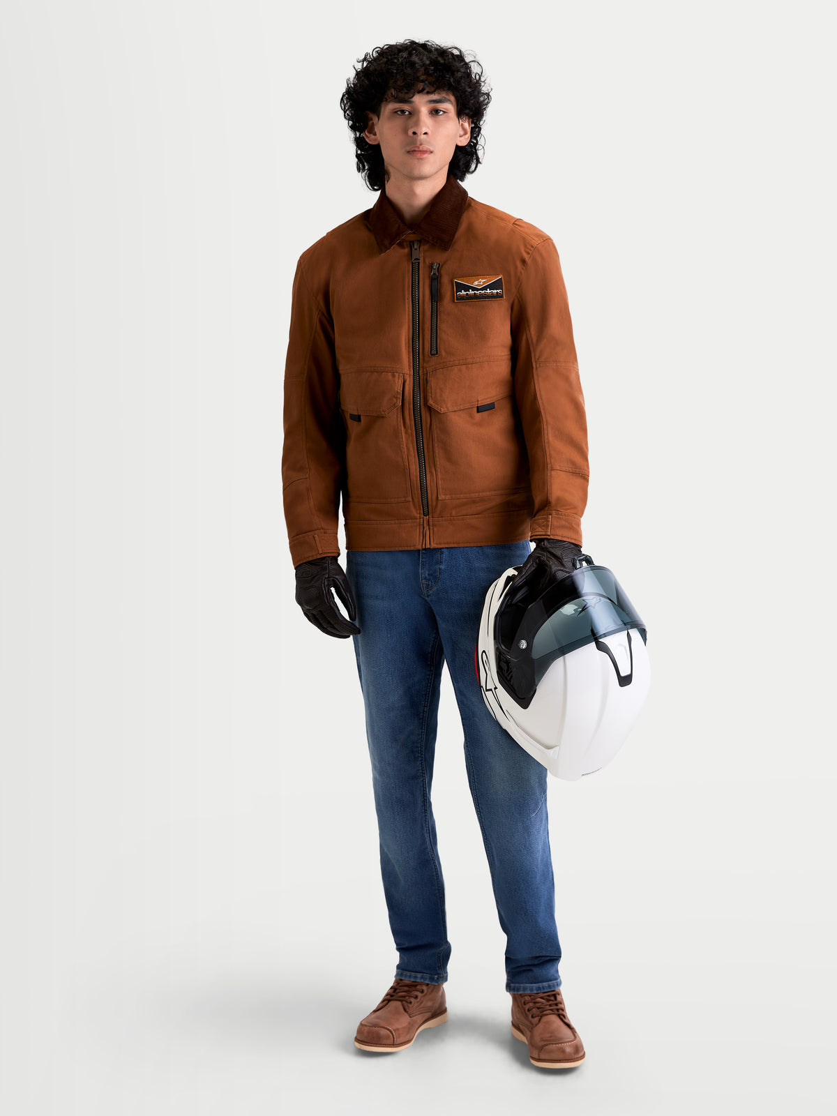 Alpinestars Flex Ast 7 Denim byxor, ljusblå motorcykeljeans för herr, bars av en modell som håller en hjälm och matchande jacka