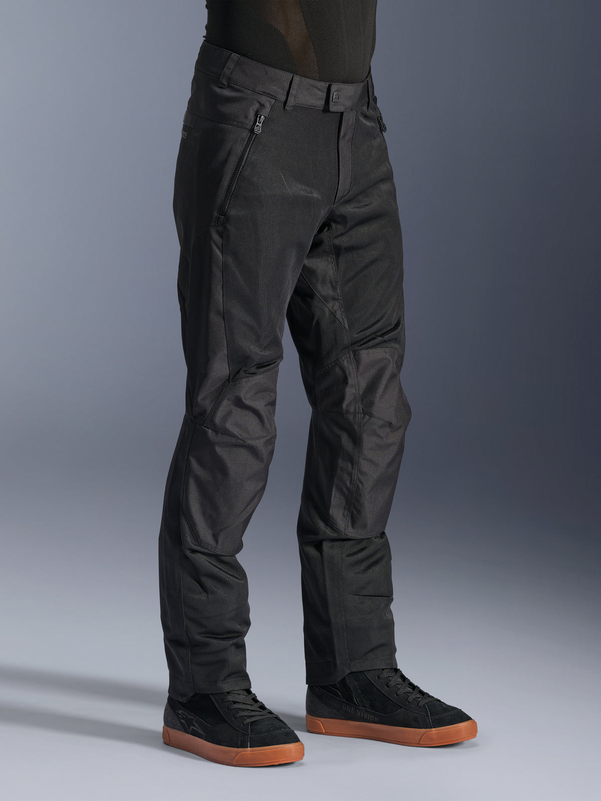 Alpinestars C-1 Air Byxor, urbana motorcykelbyxor, svarta, med ventilerande tech mesh-paneler och polytygskonstruktion, bärs med svarta sneakers, ren och funktionell design för stadskörning.