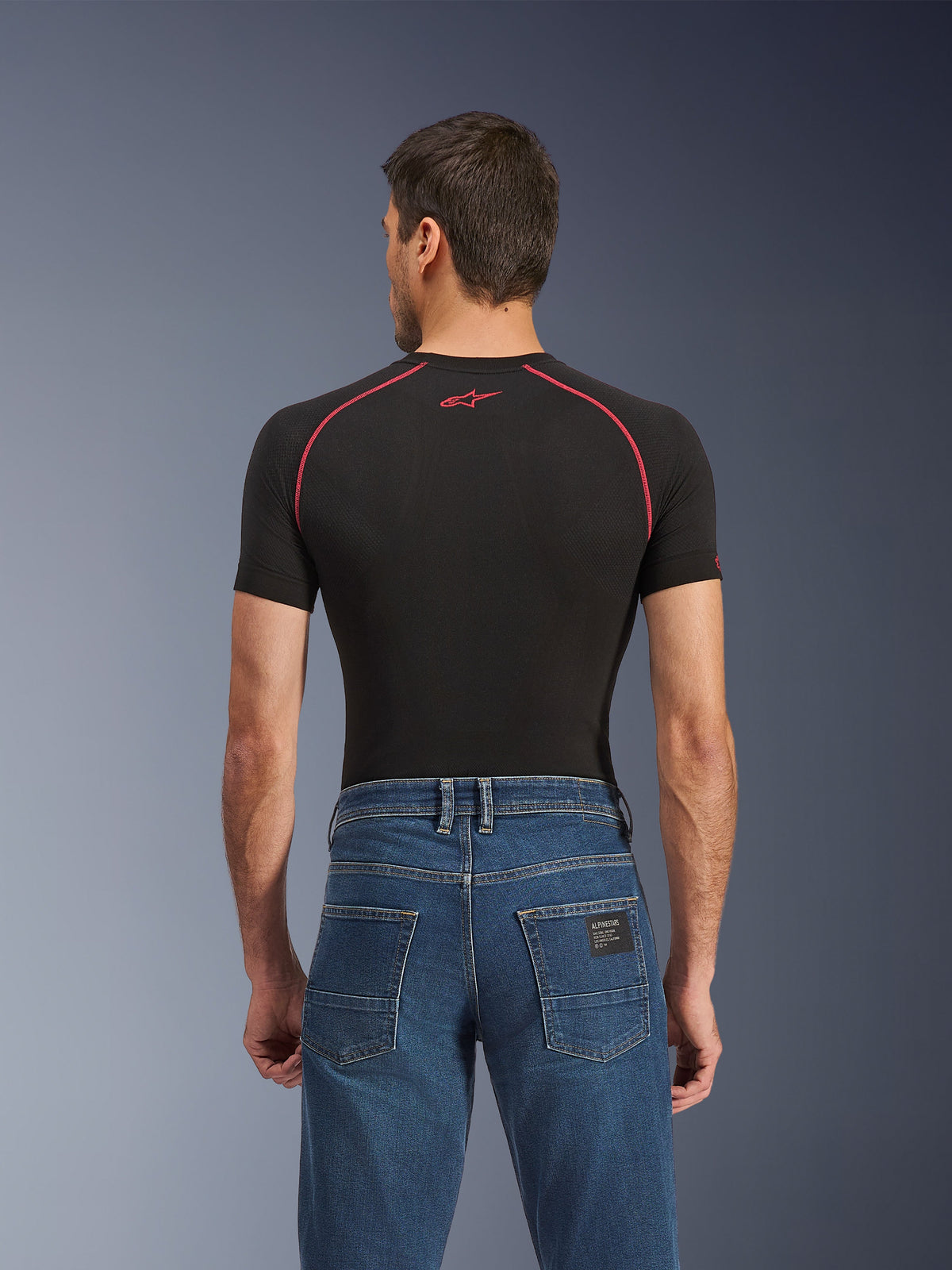 Alpinestars Flex-AST 5 Denim Pants - Short, indigo-tvättade blå motorcykeljeans, vy bakifrån med bakfickor och en liten svart Alpinestars-etikett, bärs med en svart kompressionströja med röda sömmar, avslappnade stadskörningskläder.