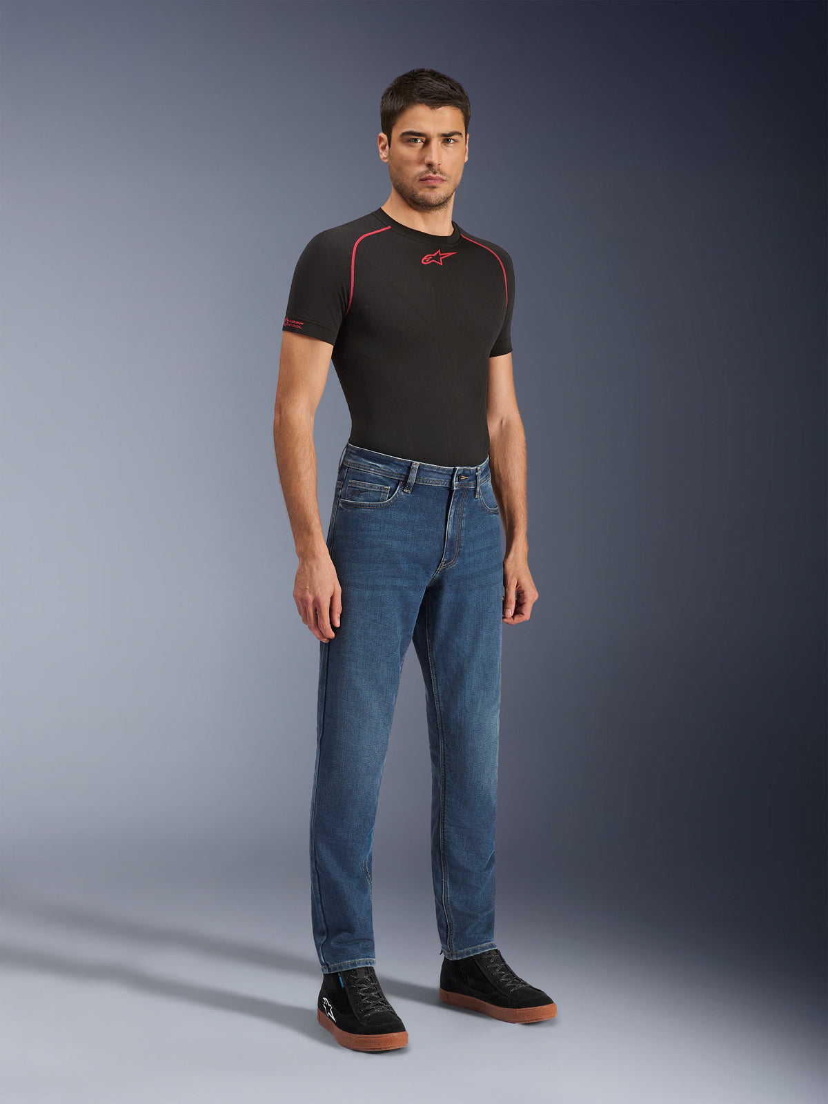 Alpinestars Flex-AST 5 Denim Pants - Short, Indigo Washed, urbana motorcykeljeans med avsmalnande passform, bärs av en manlig modell med en svart åtsittande tröja och svarta sneakers, klassisk denimstil för övergångar från väg till gata