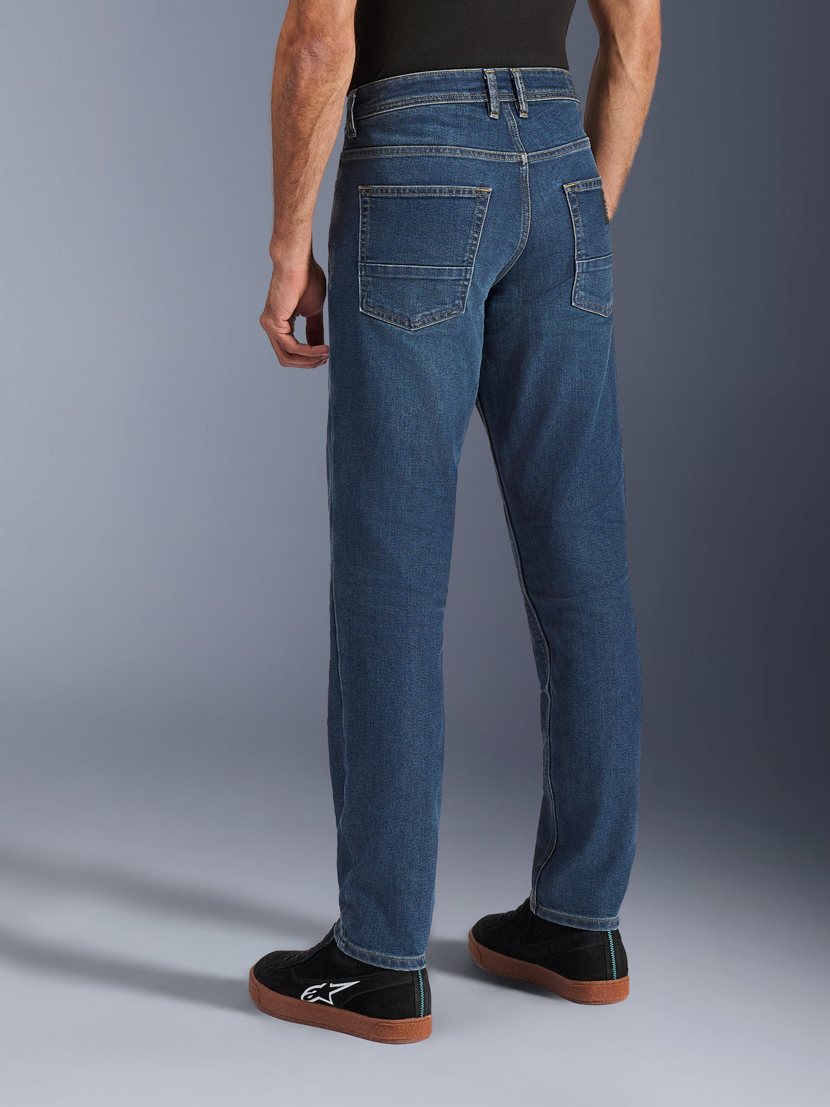 Alpinestars Flex-AST 5 Denim Pants, motorcykeljeans för herr för stadskörning i tvättad indigoblå, sidovy bakifrån på modell som visar den avsmalnande passformen, bakfickor och en avslappnad stil i stretchjeans.