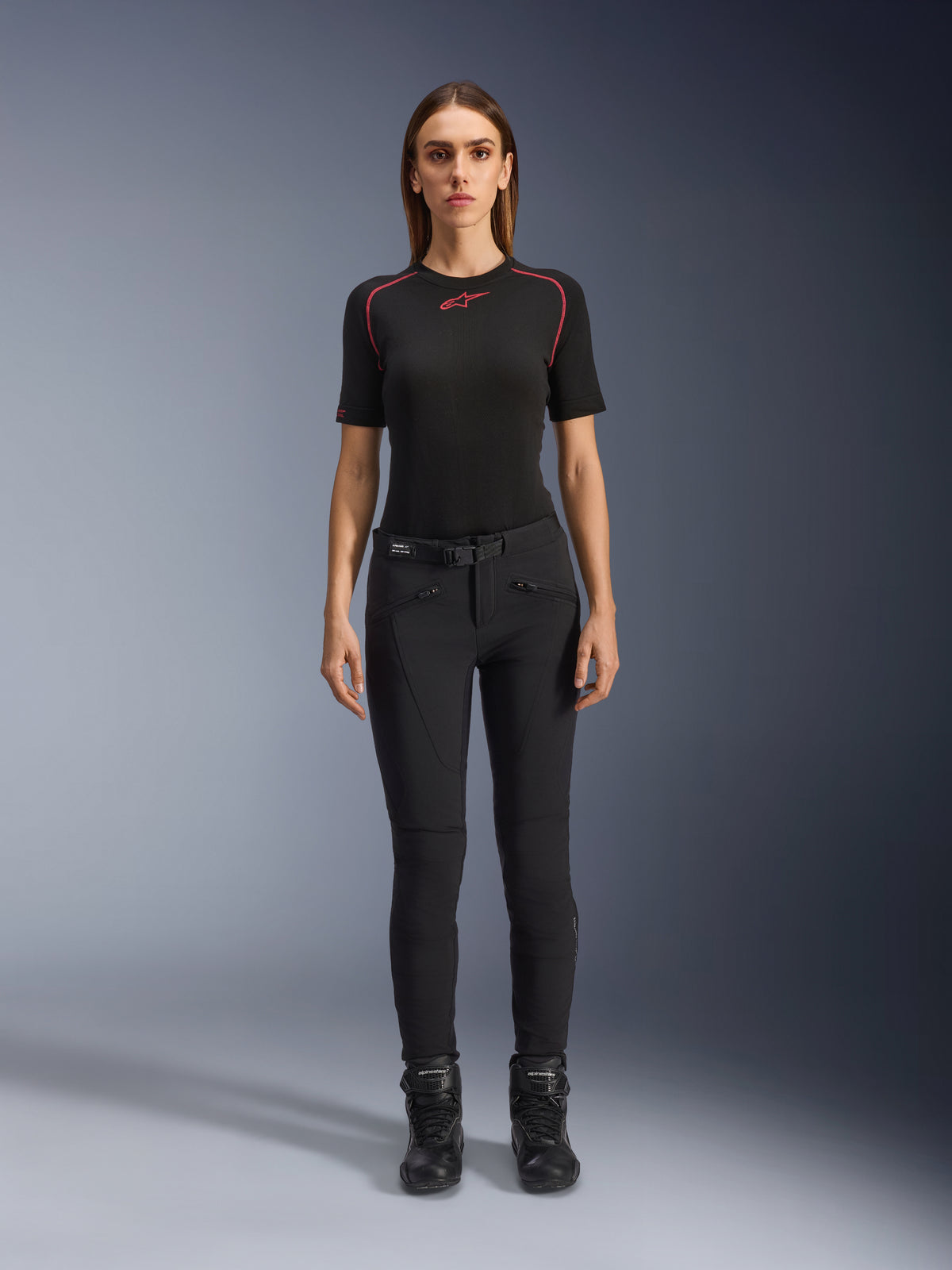 Alpinestars Alamosa dambyxor, svarta motorcykelbyxor i slim-fit, visas på en modell vänd framåt, med framfickor med dragkedja och ett integrerat midjebälte, minimalistisk streetwear-inspirerad stil för stadskörning