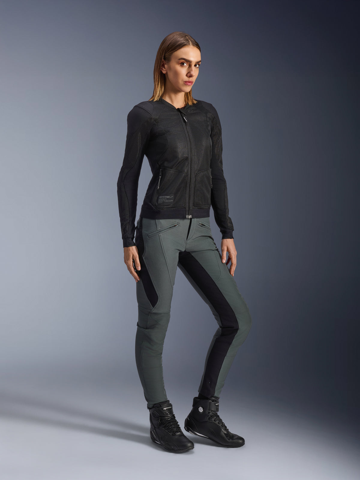 Alpinestars Alamosa dambyxor, slim fit motorcykelbyxor, grå och svarta, urban textil med stretchpaneler, bärs av modell med svart meshjacka och MC-stövlar.