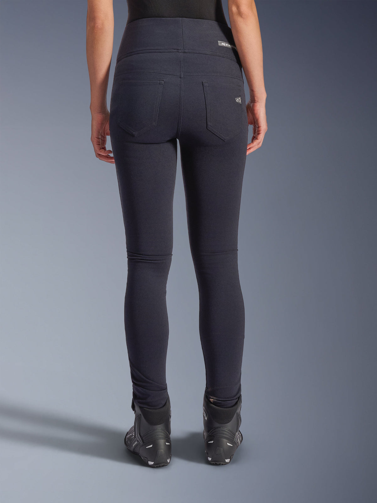 Alpinestars Stella Flex-AST leggings, urbana motorcykelbyxor, svarta, sedda bakifrån med hög midja och smal passform, två funktionella bakfickor med subtil logotyp, stretchigt textilmaterial, bärs med svarta mc-skor.